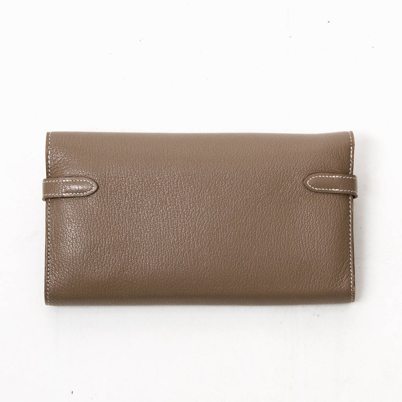 Superb Hermes Kelly Long wallet that is often carried as a clutch.  
Features 12 credit card slots, large coin zippered pocket
2 pocket for bills and a large notes pocket. 
The wallet will be shipped with its box and ribbon.