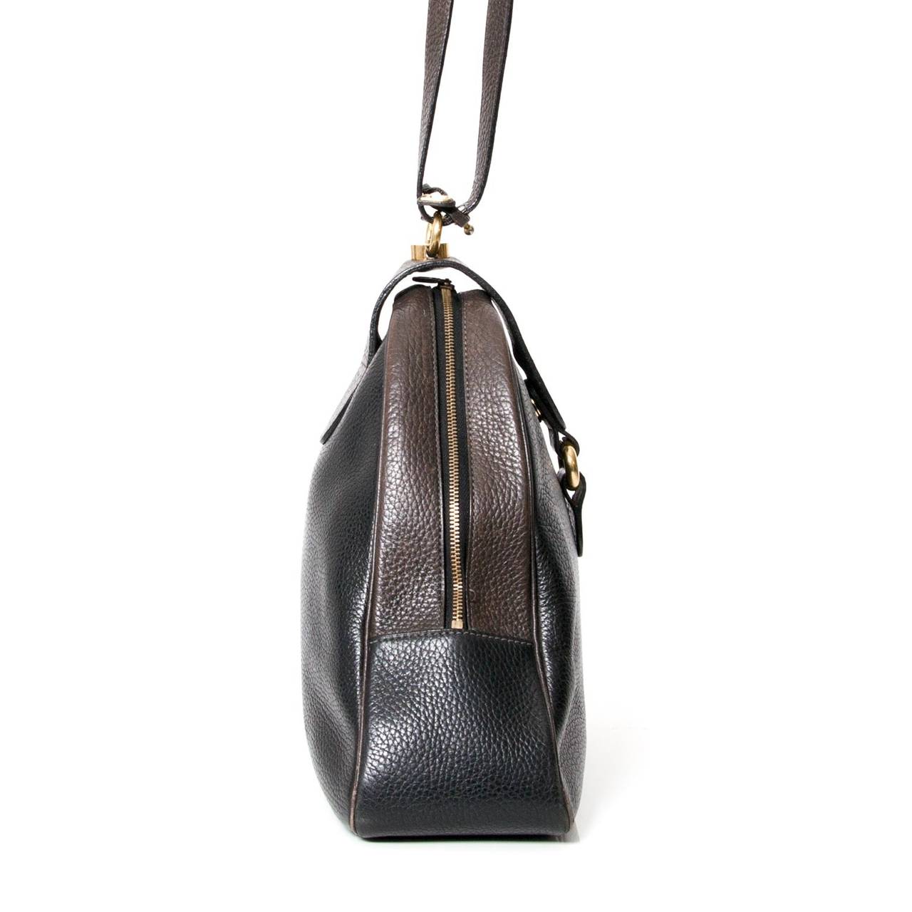 A very original and stylisjh Delvaux shoulder bag in black and dark brown wide grained calfskin. With pale gold-tone hardware with a single shoulder strap at the top. Interior suede lining.