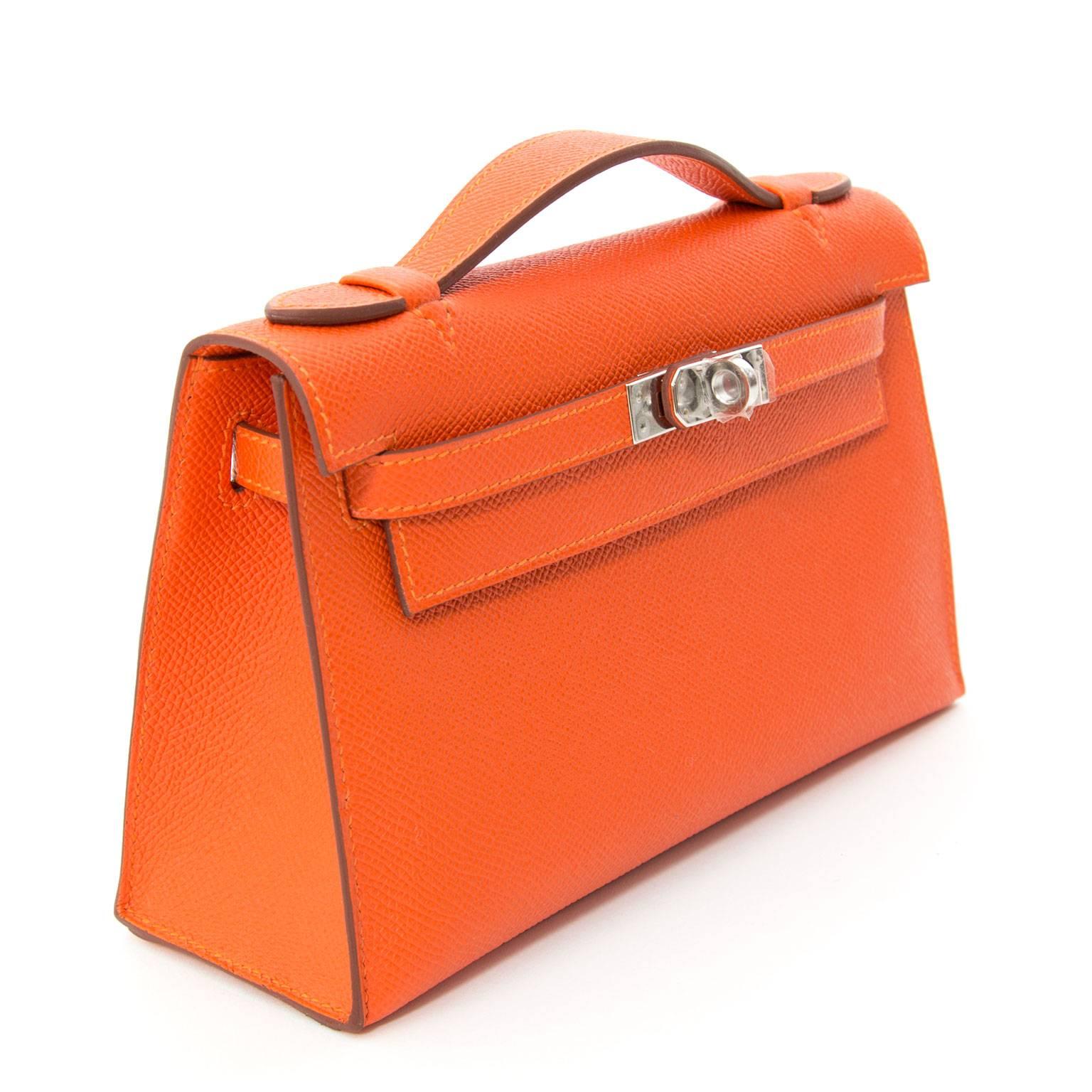 Charming Hermès Kelly top handle clutch. This miniature Kelly pochette is made from durable Epsom leather. The perfect material for a bag to keep its structure. 
The paladium hardware looks modern on this new Hermès color 'Feu' a very vibrant,