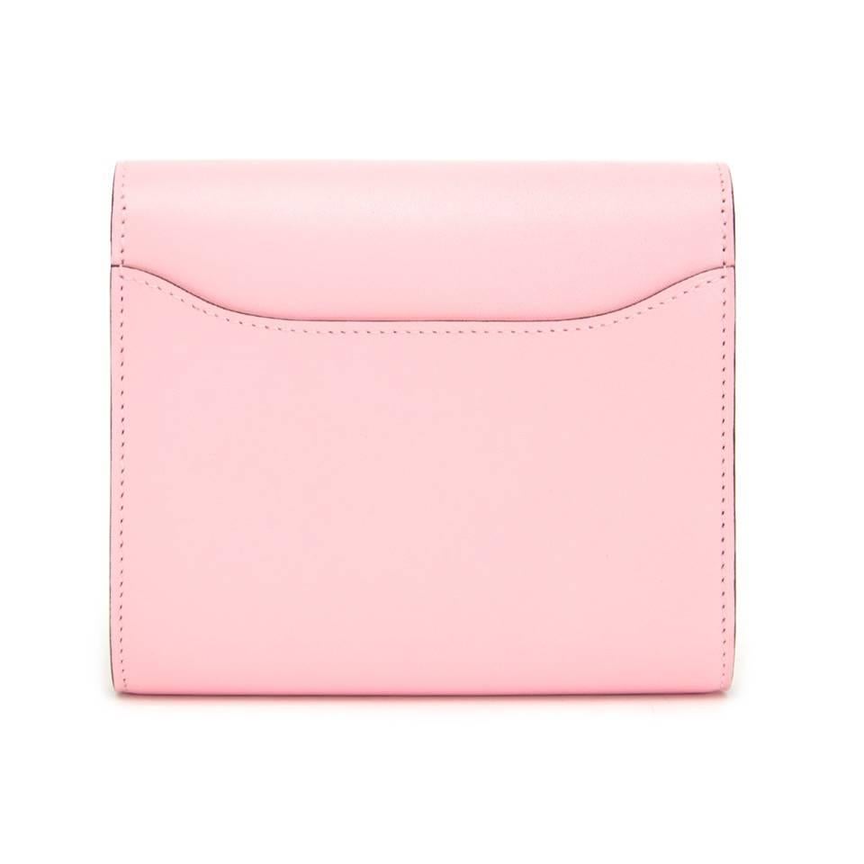 Store fresh Hermes Constance Compact wallet in baby pink. The stunning item contains two compartments and a zip pocket. Exterior features patterned pink Hermes ‘H’ as a closure and a slip pocket on the back. 

Comes with original box and receipt. 