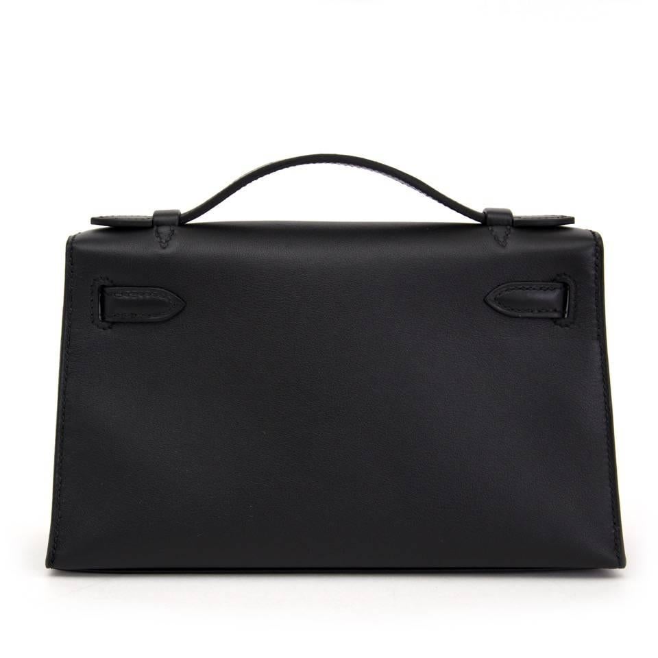 The Hermès Pochette Kelly Veau Swift comes in a black leather with palladium hardware. 
The adorable design contains a front flap with two straps, a toggle closure and a single flat handle. 
The bag is accompanied by: Hermes box, dust bag,