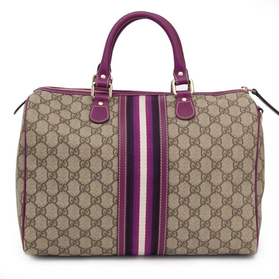 This Gucci Joy Boston with purple details is one of a kind. The bag is finely crafted of GG monogram canvas in cowhide leather and detailed with purple trim and rolled top handles. The interior is accessed through a golden zipper and contains a