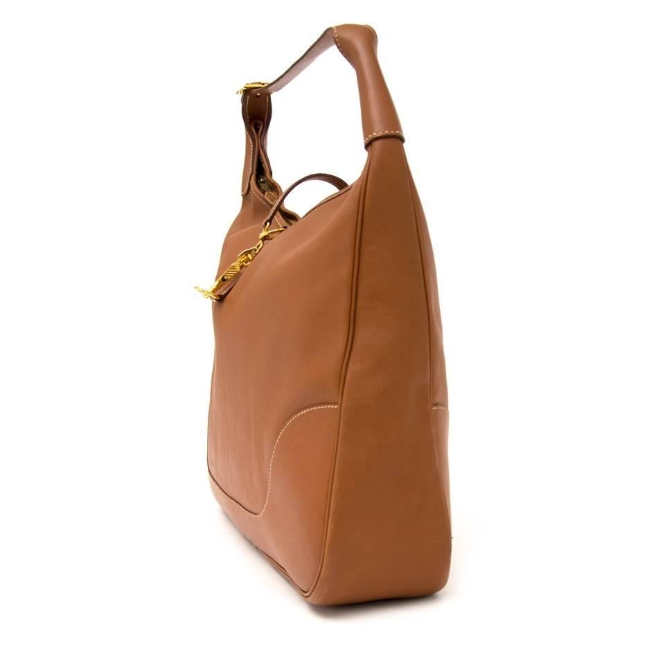 The Hermes Trim shoulder bag comes in a beautiful cognac leather with gold-toned hardware. The wide and practical interior is accessed through a click system and zipper. Perfect bag to carry during daytime, since it offers a lot of space. 