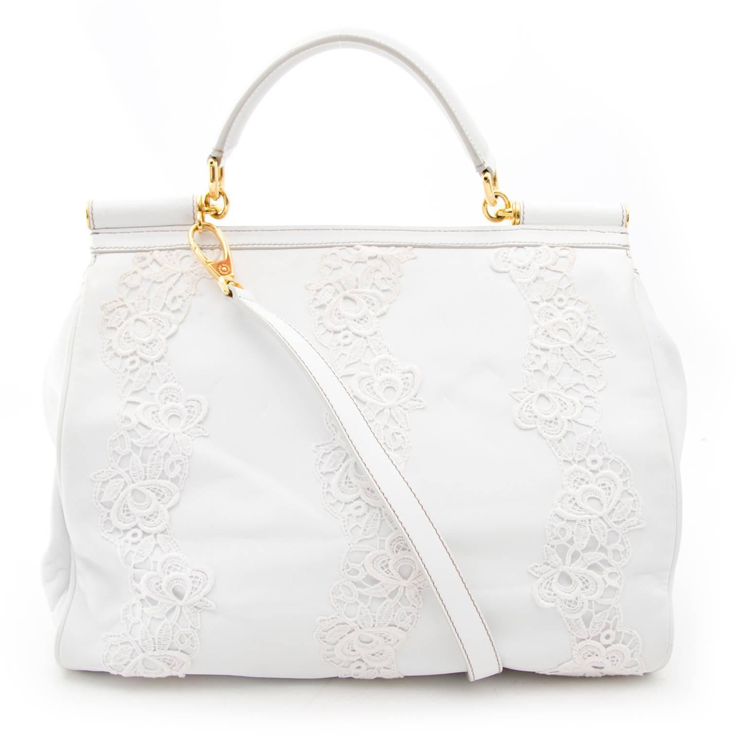 Dolce & Gabbana created a perfect bag to match your summer looks wtih this gorgeous white piece.
The white leather is combined with lace parts and finished with shiny gold-tone details.
Open this beauty with the push-buttons beneath the front flap