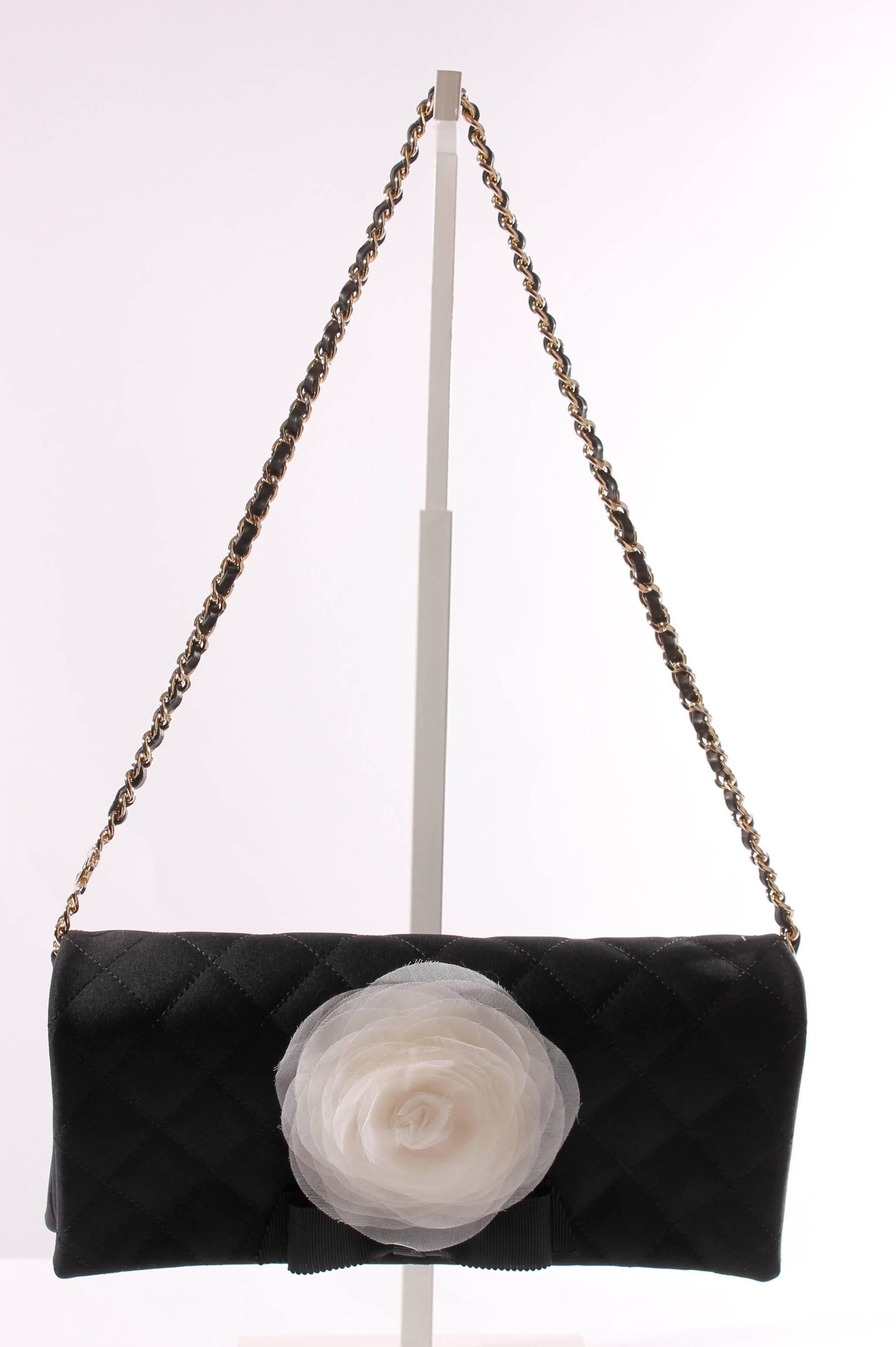 
Ooooh la la! This is true beauty! A wonderful and exquisite evening clutch by Chanel in matte black satin with a white chiffon camellia flower. Underneath the flower a black bow is attached.

This cuty is entirely quilted, accept for the sides.