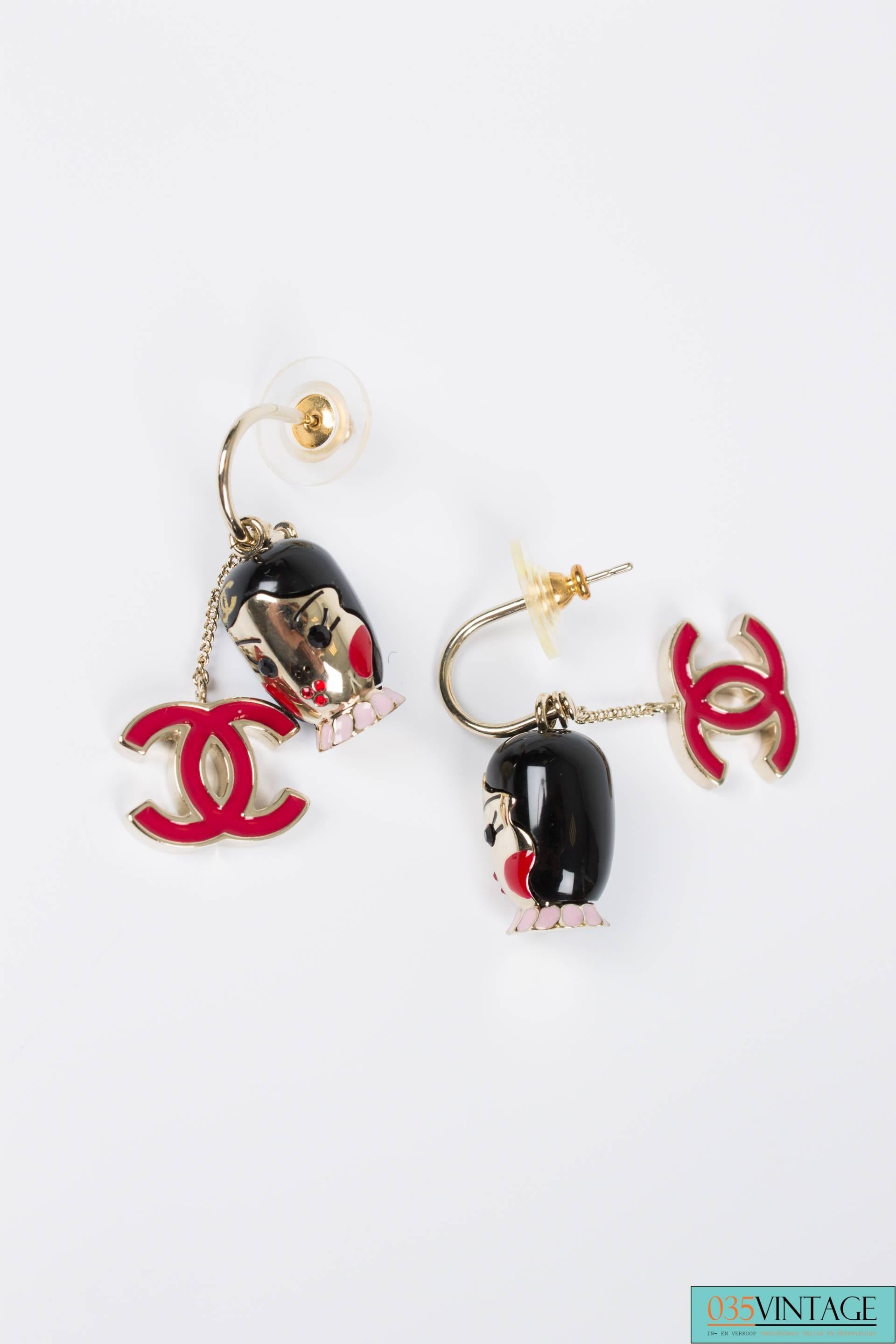Earrings with charms by Chanel, extraordinary pretty!

The little silver earrings have a pin, the charms can be easily removed or changed. One charm holds a woman's head with black hair, red blusher and a red crystal mouth. A pink collar and a
