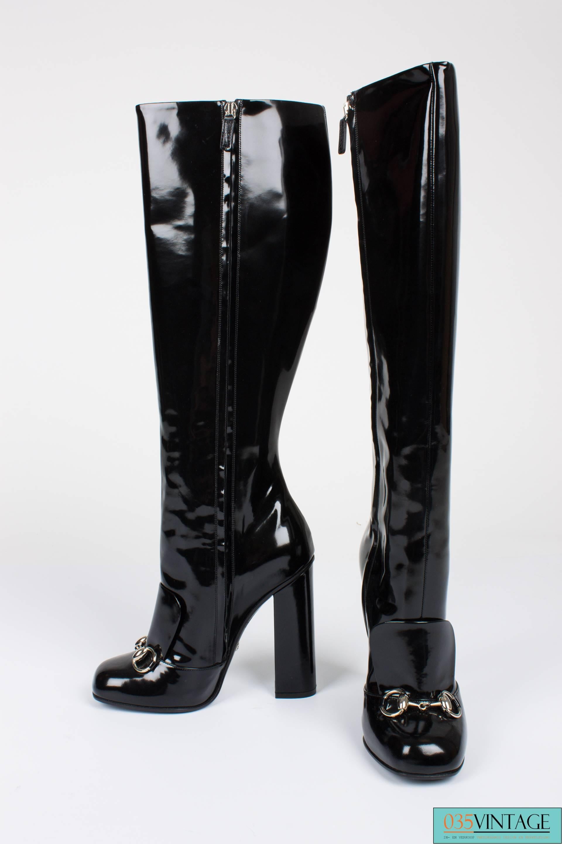 Soooo nice! Gucci Lillian boots in black patent leather, high heeled and a zipped shaft.

A silvertone horsebit on the foot, stirdy straight heel that measures 12 centimeters. Slightly square toe, shaft measures as much as 43 centimeters. Lined