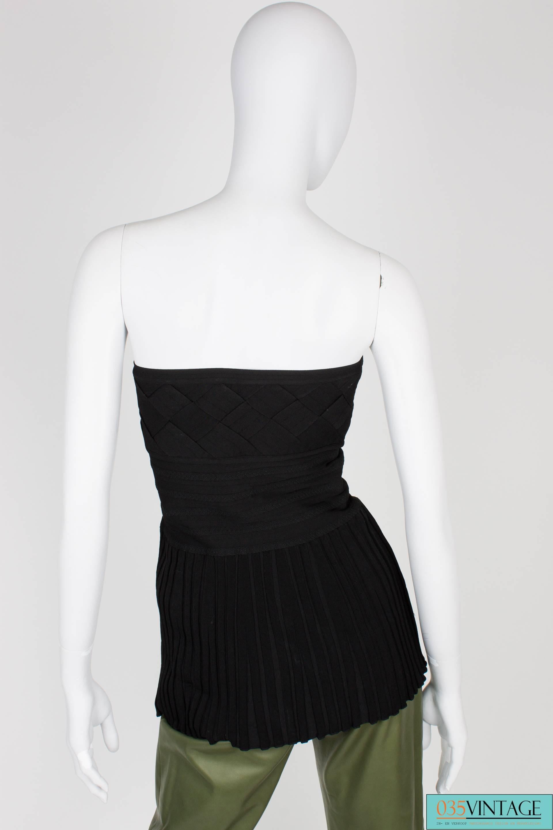 Beautiful strapless top by Chanel, this one goes with anything!

The upper part is woven, wide straps were used. The part in the middle creates firmness and is very tight to the body. The lower part is loose and pleated. A matte silver Chanel