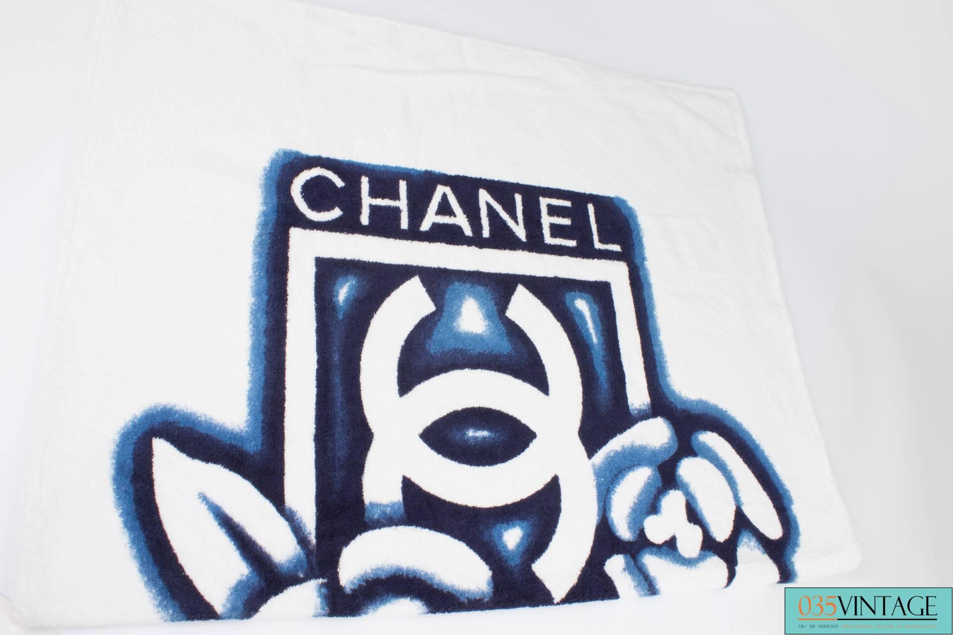 

Large square beach bag by Chanel made of dark blue terry cloth, white interlocking CC's on the front and back.

This bag has two handles that measure 36 centimeters each. On the inside lined with smooth dark blue fabric. In between the exterior