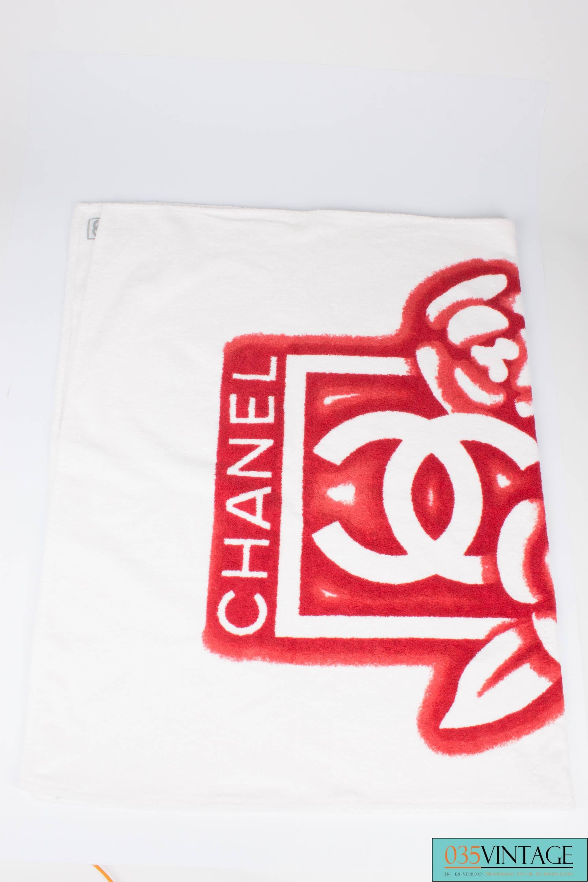 Large square beach bag by Chanel made of red terry cloth with white interlocking CC's on the front and back.

This bag has two handles that measure 36 centimeters each. On the inside lined with smooth red fabric. In between the exterior and the