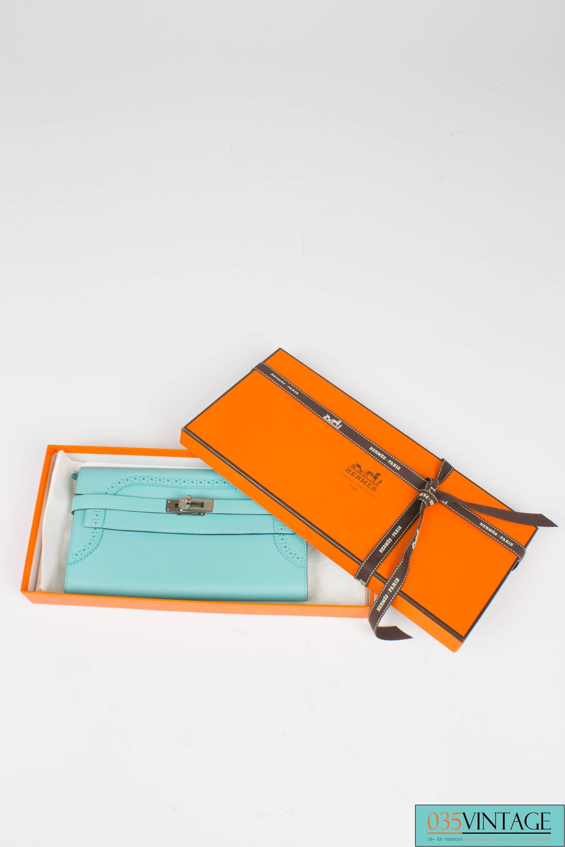 This one is sooo beautiful! It is the Hermès Kelly Portefeuille Classique Ghillies Veau Swift in the color Blue Atoll. It is a limited edition...

An oblong wallet which also can be used as a small clutch. Silver hardware on the front, the