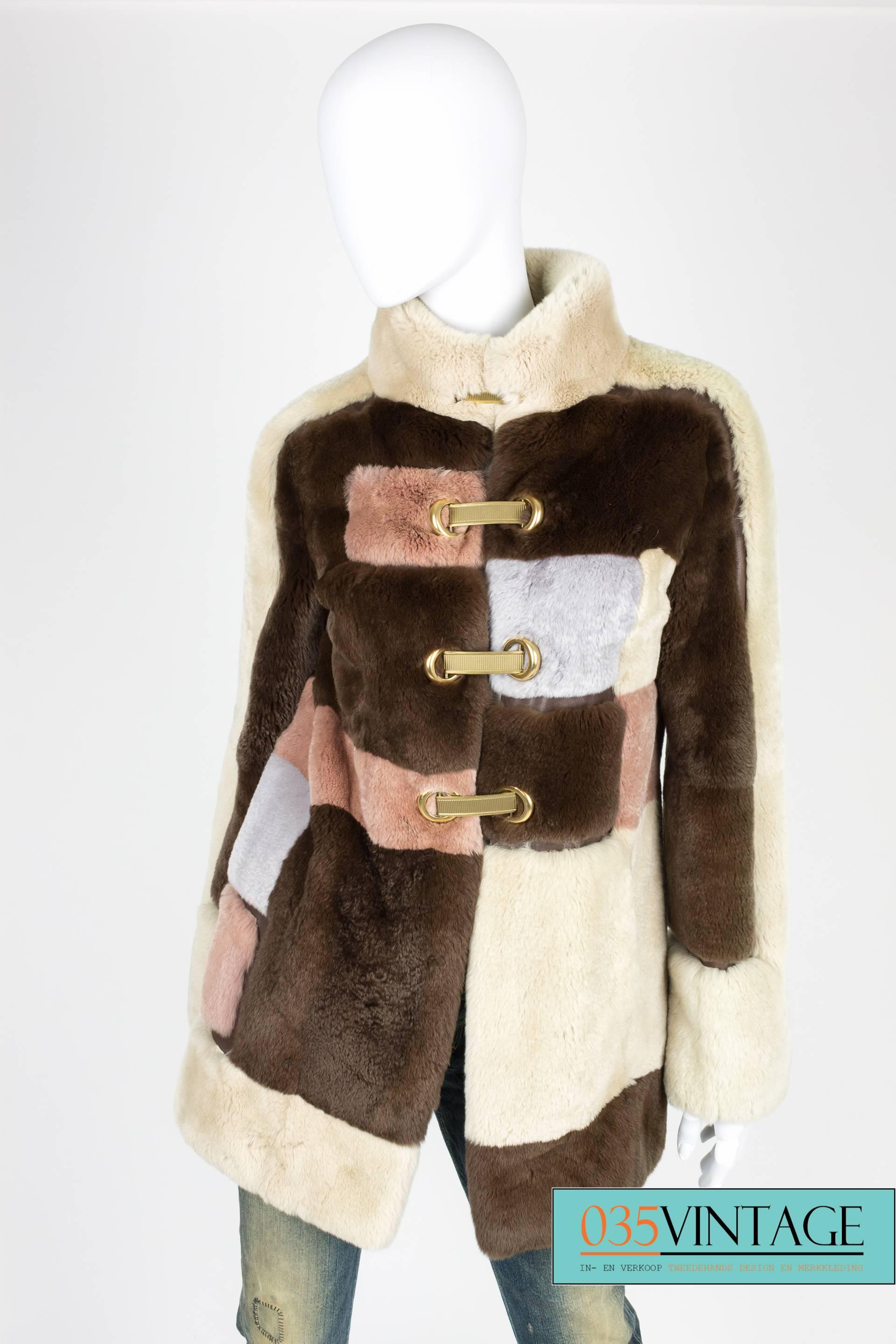 Supple and light fur coat with leather detailing by Emilio Pucci in a beautiful square pattern.

The squares are dark brown, beige, gray and pale pink. In between the squares you will find dark brown leather parts. Mandarin collar and welt pockets.