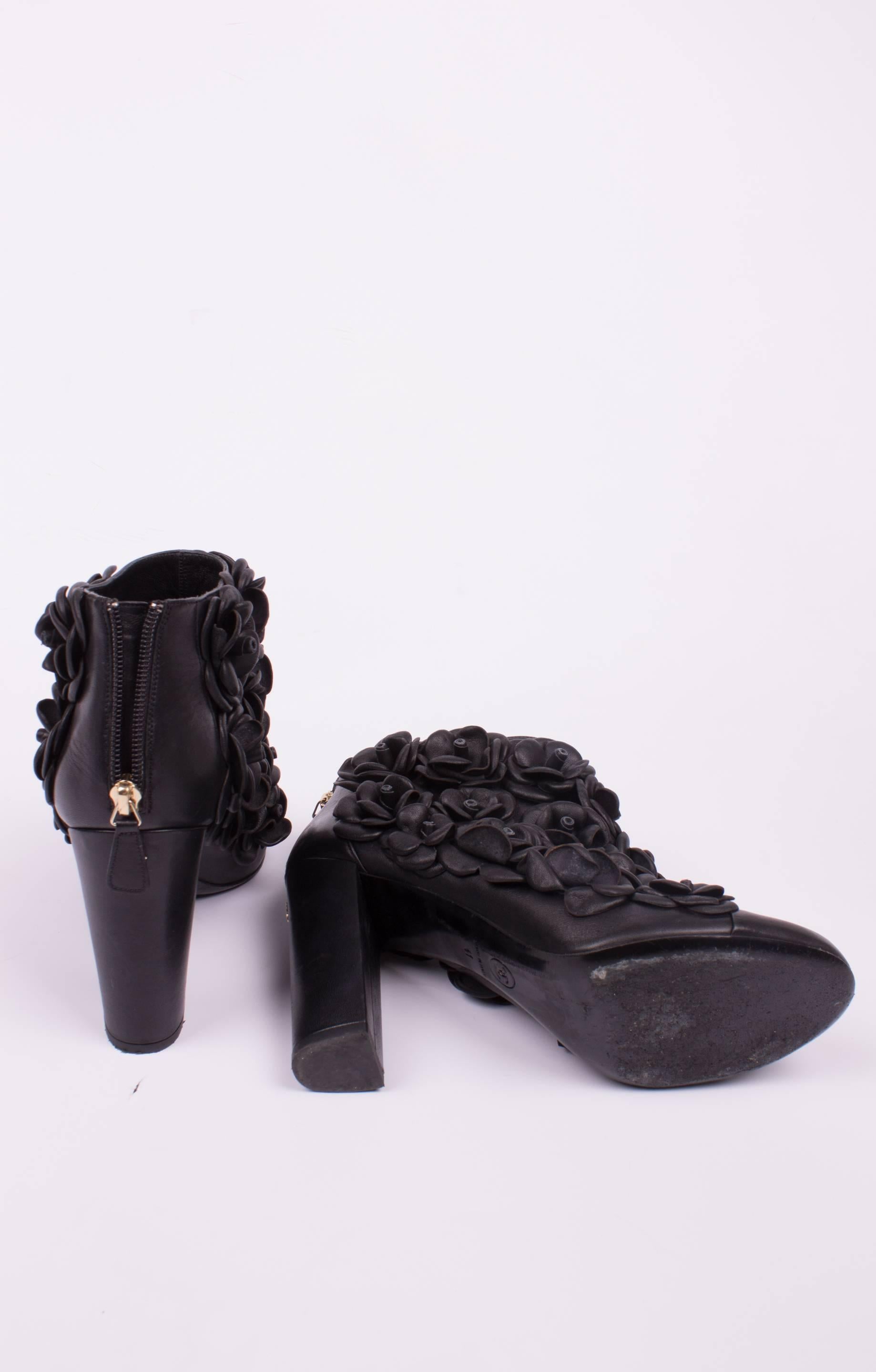 Incredibly beautiful black leather boots by Chanel covered with Camellia flowers. Sooooo nice!

These ankle boots have a sturdy and straight heel that measures almost 11 centimeters. On the back of the heel a small golden metal CC-logo. A round toe
