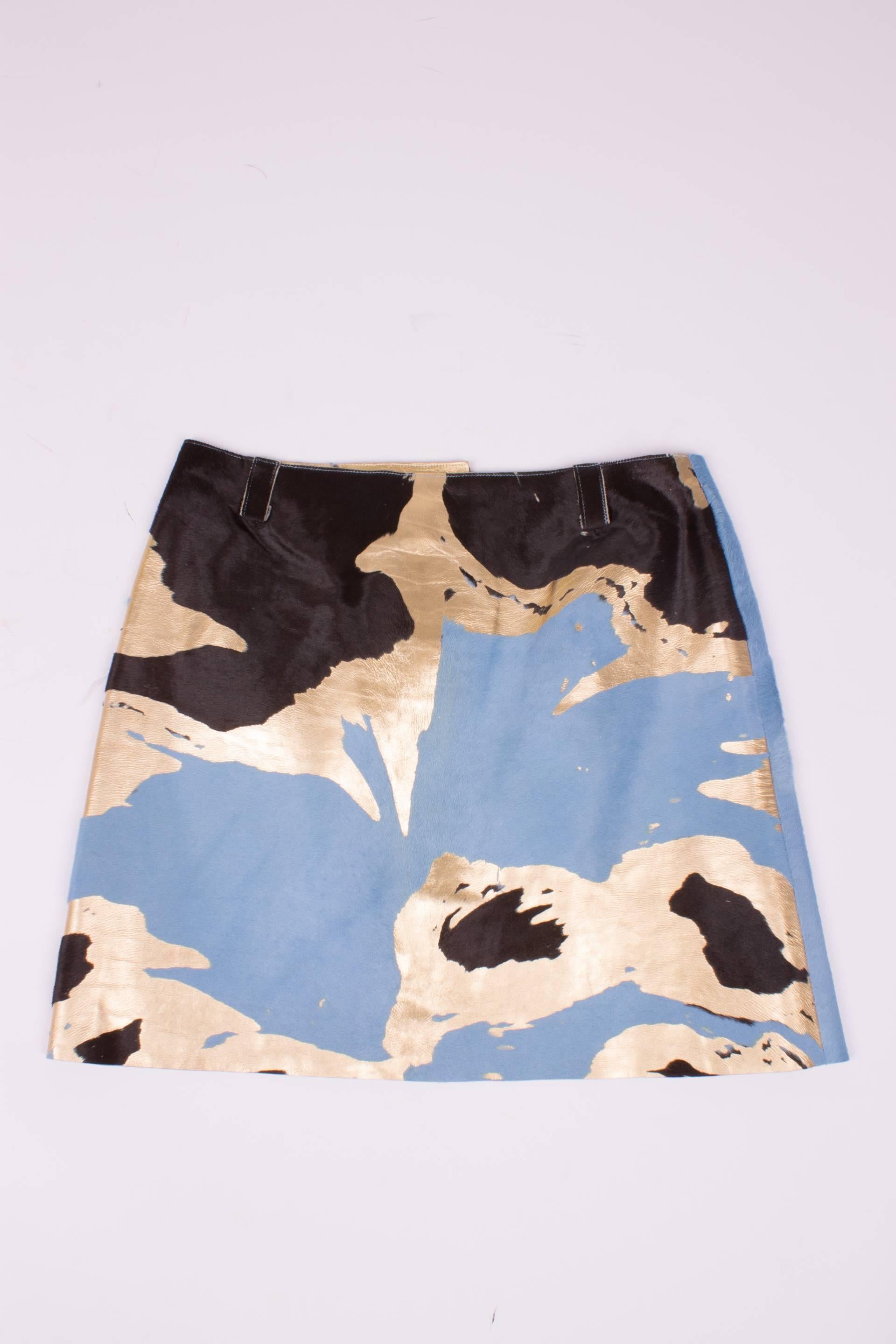 Short skirt by Chanel made of calfskin leather in light blue, dark brown and gold.

This skirt has three button closure, these buttons are square and matte golden. On the outside the calfshair shows in the light blue and dark brown parts. The golden