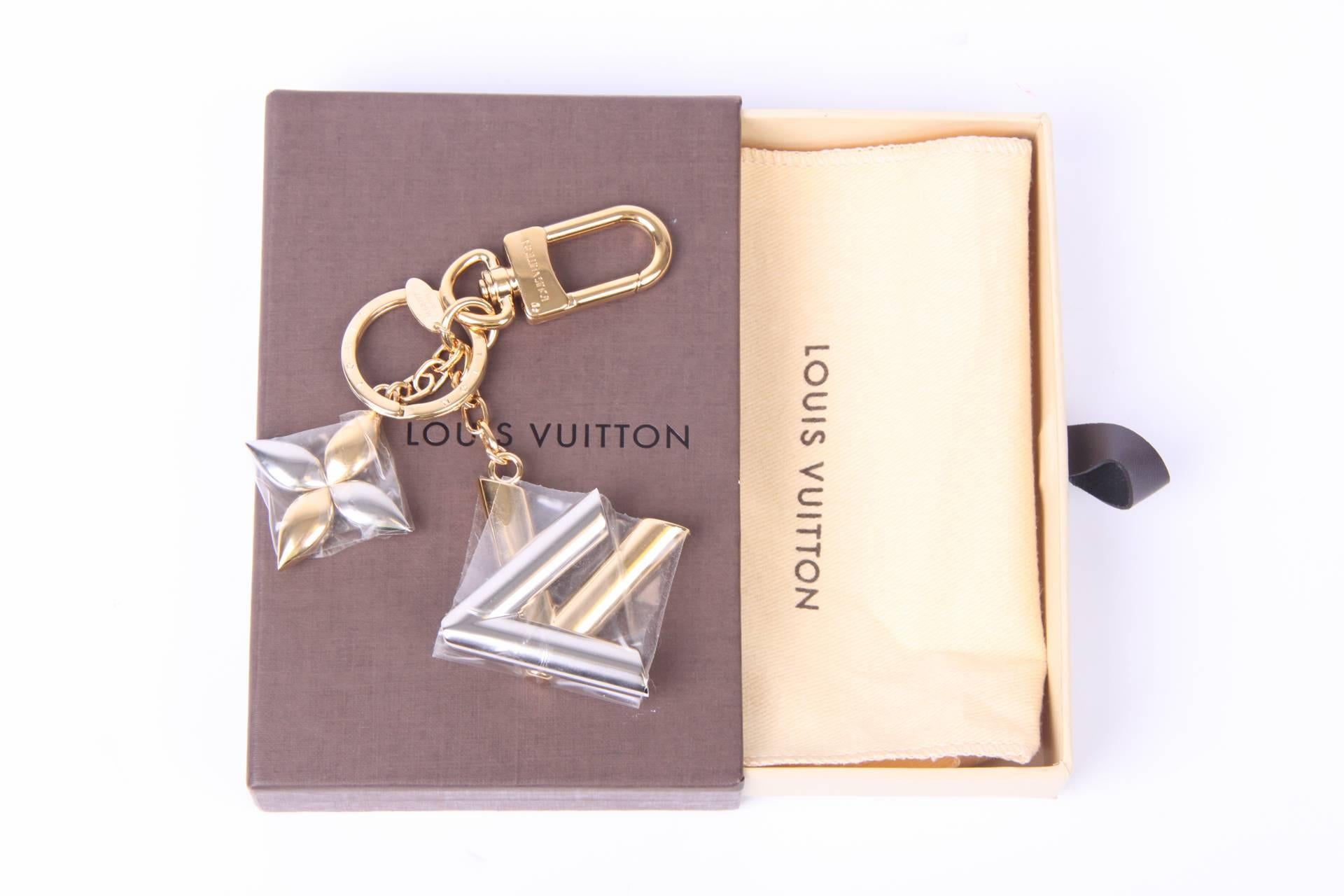 A key chain by Louis Vuitton! How cool is this one?!

Two large charms: one clover and one LV monogram. Both crafted in gold- and silver-tone. The ring and the little hook are executed in gold-tone.

In perfect condition, brand new! The protective