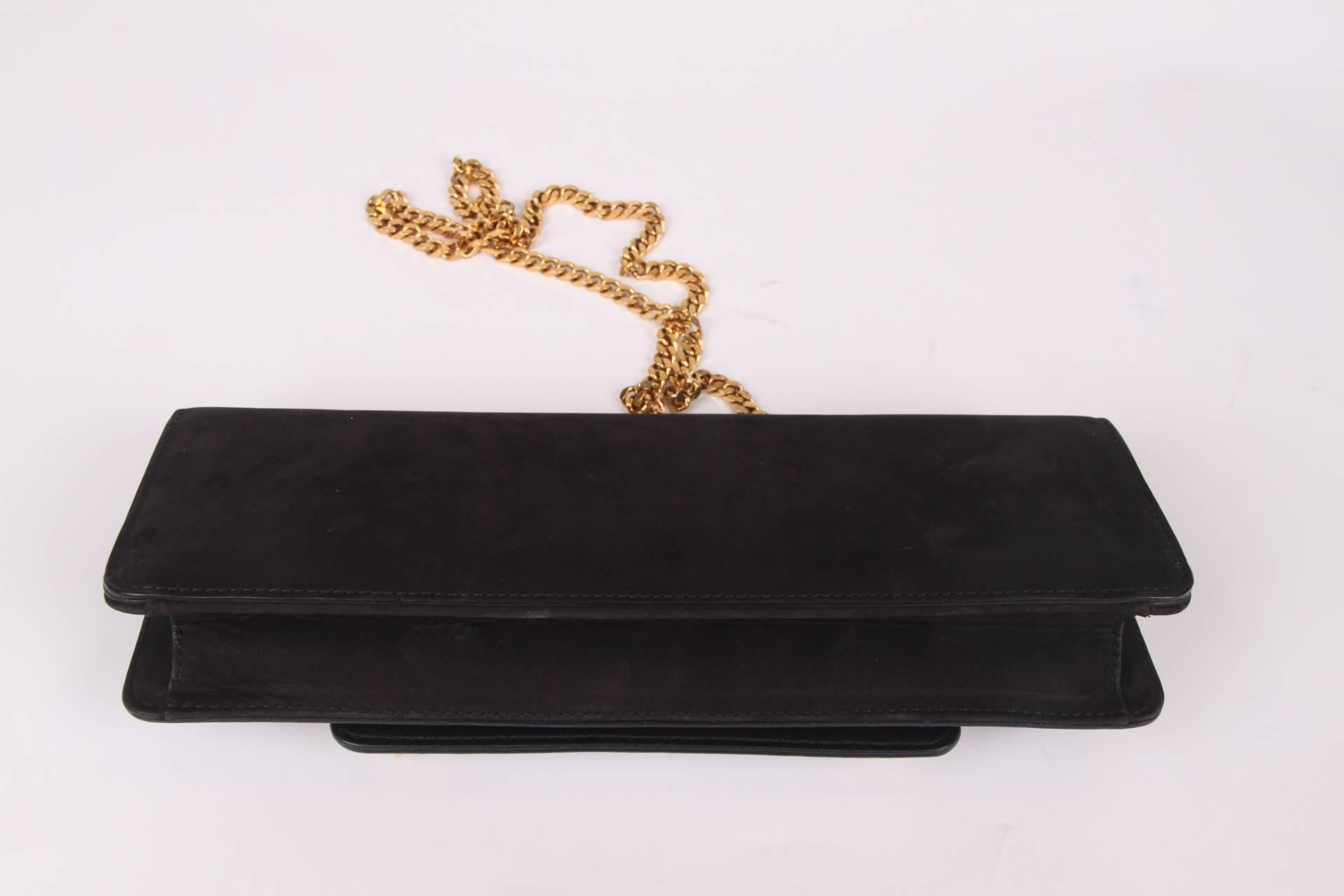 From the Tigrette collection by Gucci; a black nubuck leather clutch bag. Fancy!

This bag is rectangular, has a detachable gold-tone chain shoulder strap and flap closure with two black and white enamel tiger heads. The eyes have red crystal