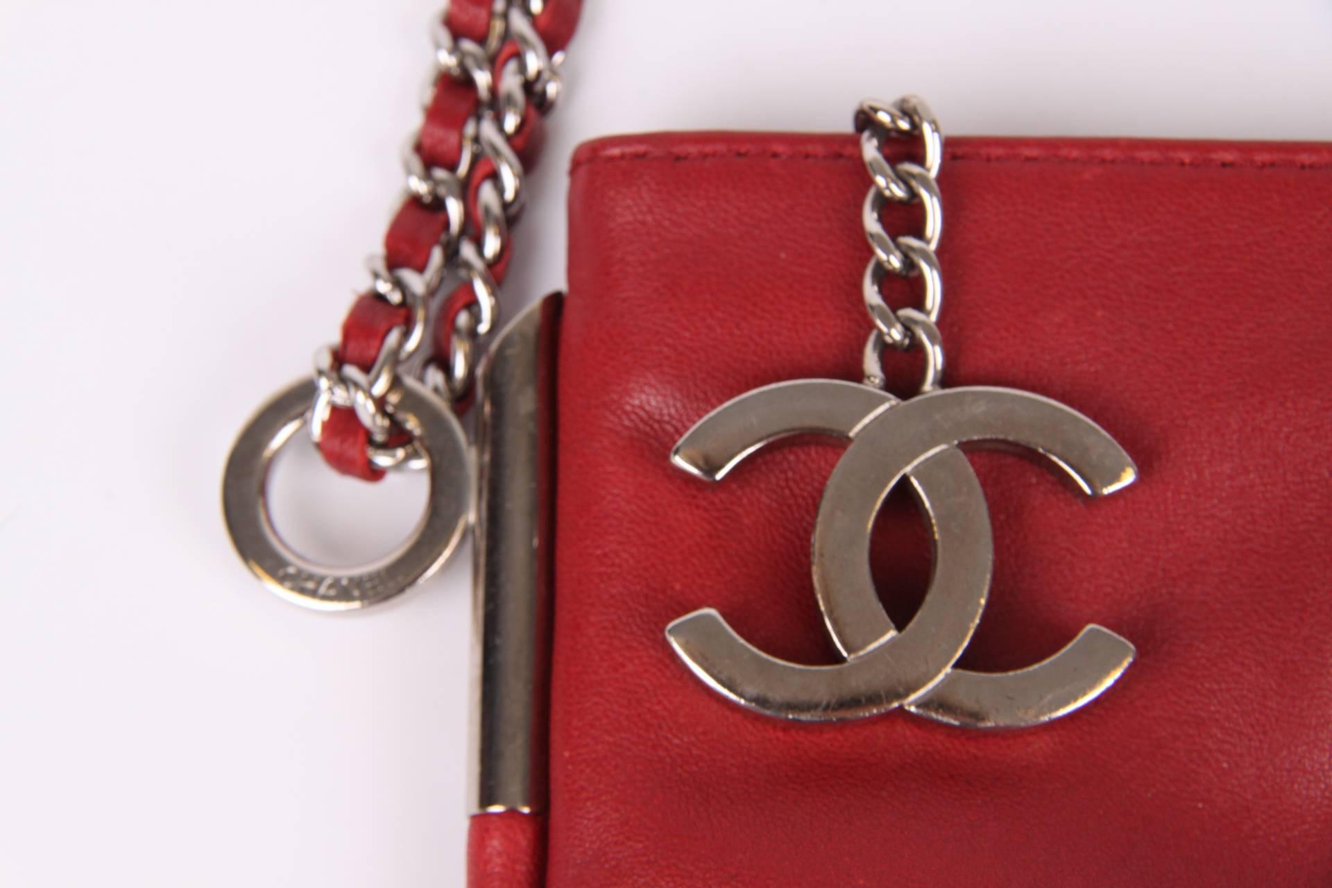 A wonderful clutch by Chanel, we love it!

Nice and handy size with a handle and a zipper on top, a large silver CC dangle is attached to it. An embossed CC logo at the front of the bag. Silver hardware.

The back of this dark red leather clutch is