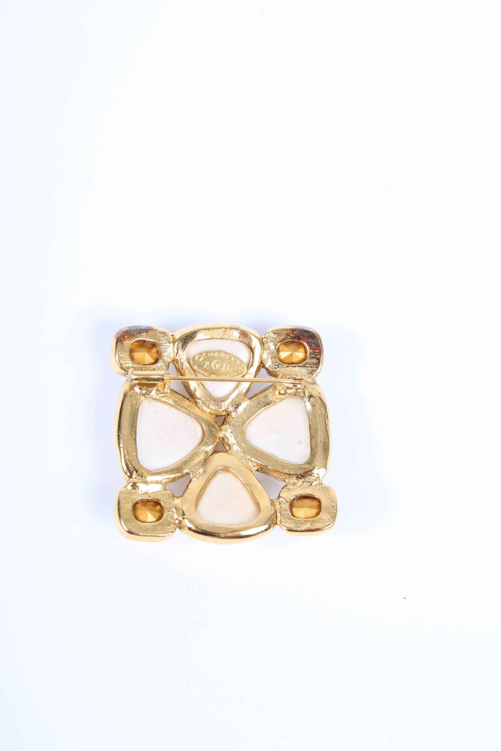 This is an authentic Chanel brooch executed in gold-tone metal with pearls and crystals.

The large faux pearls together have the shape of a four leaf clover, four white crystals on the corners. The back is gold plated and has a large pin. On the