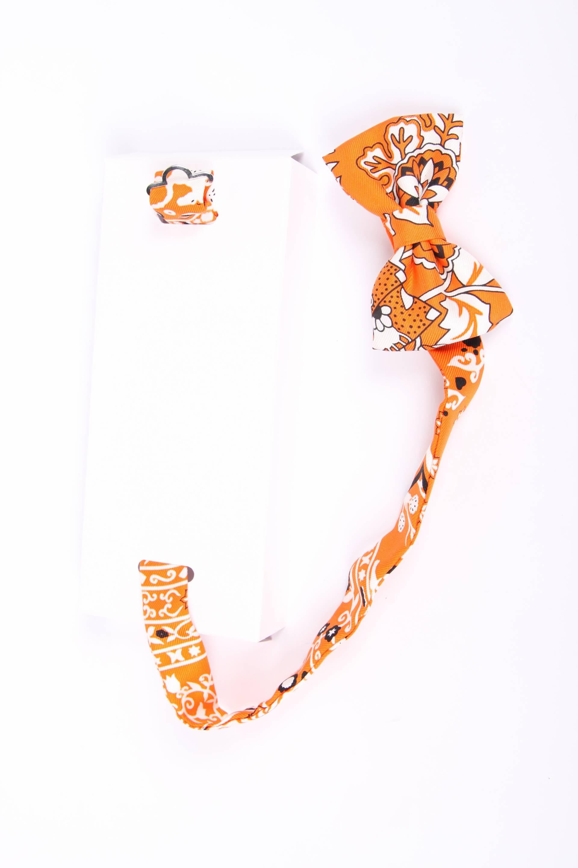 Special bow tie by Hermès in orange, black and white silk.

A real statement to wear with a white blouse, but this bow tie can also be worn around the wrist. Has an adjustable strap, one size fits all.

New and never been worn, comes with