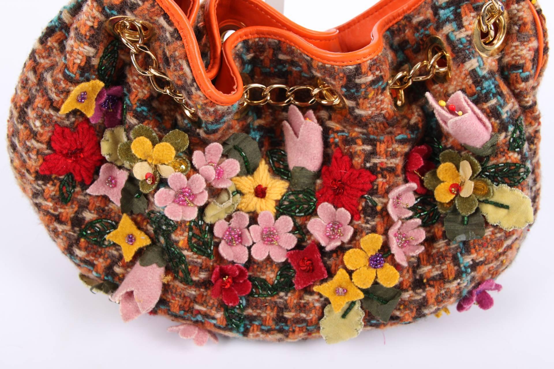 Very special bag by ETRO crafted in multi coloured boucle covered with flowers and beads.

The handles are executed in orange and brown leather, gold-tone hardware. Magnetic snap button closure on top, fully lined with shiny green fabric. On flat