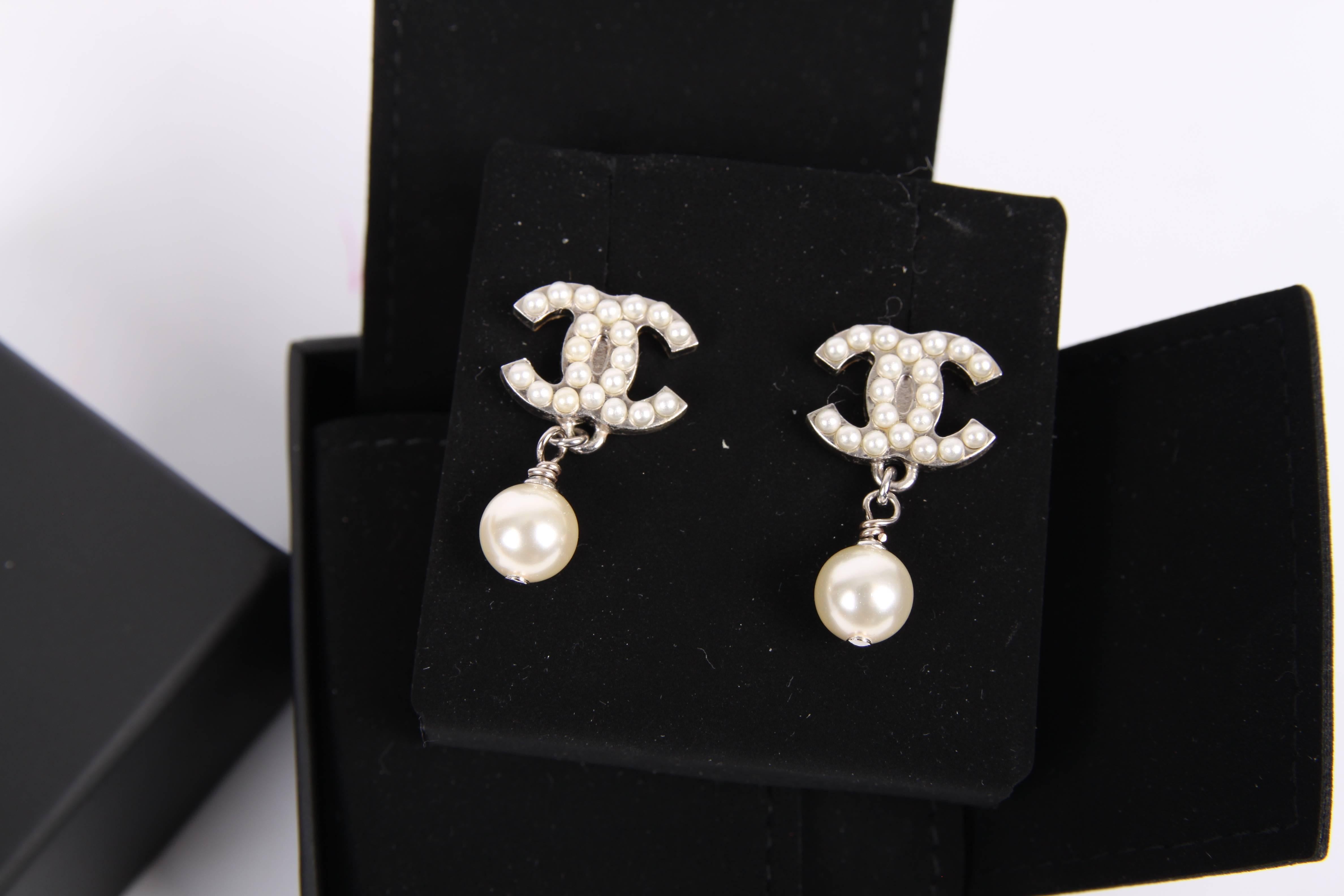 Elegant earrings by Chanel, these are classic!

A silver-tone CC logo covered with mini pearls, underneath a larger faux pearl is dangling. This pair goes with everything, is brand new and never been worn. Comes with luxurious little Chanel