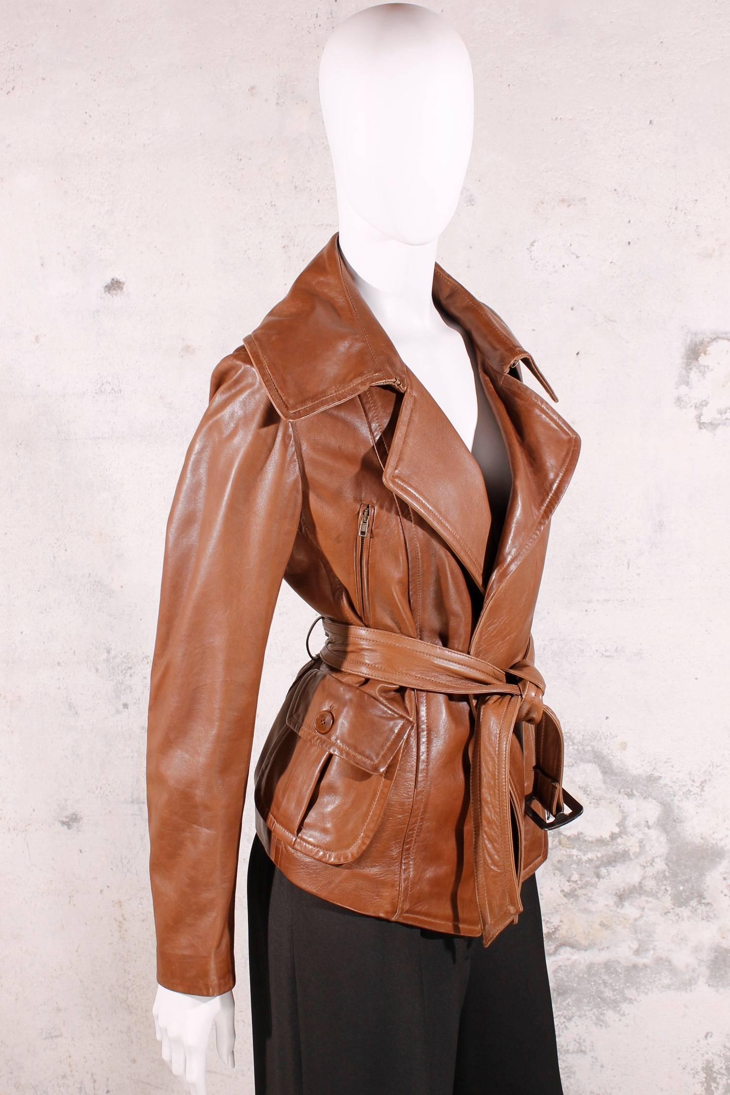 Beautiful brown leather jacket from Donna Karan in size US8/GB10/IT42. This jacket has a large lapel, epaulettes on the shoulders and oblique zippers at the chest. Flap pocket below with a brown button.
There is a loose belt with a buckle to close