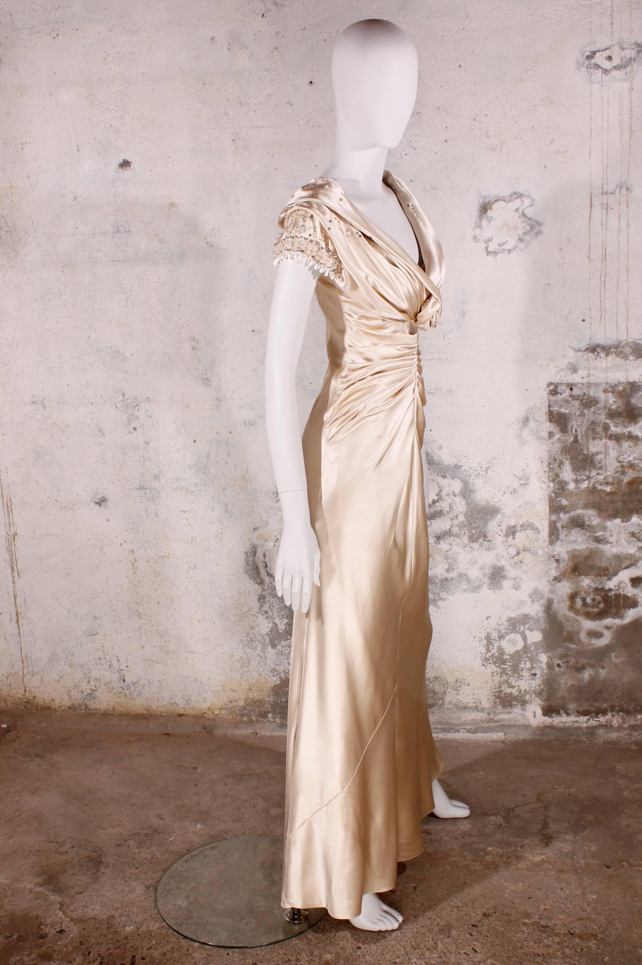 Long and very elegant evening gown of Christian Dior in a beautiful shiny champagne color. The dress is bias grain cut and a tiny bit longer at the back.
It has sequins, crystals, beads and pearls on the short sleeves and the waterfall collar on