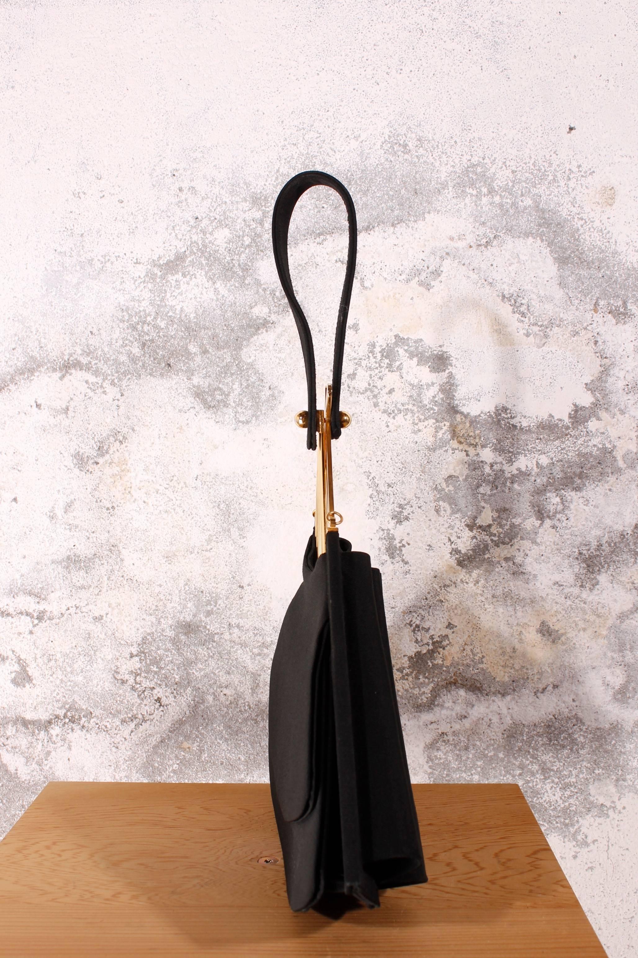 This KARL LAGERFELD beauty is a 100% authentic vintage collectors item from the 1980s.

The black satin fan handbag from KL can be used as a glamorous evening bag, It is made of black satin and has golden details.

One of the most collectable