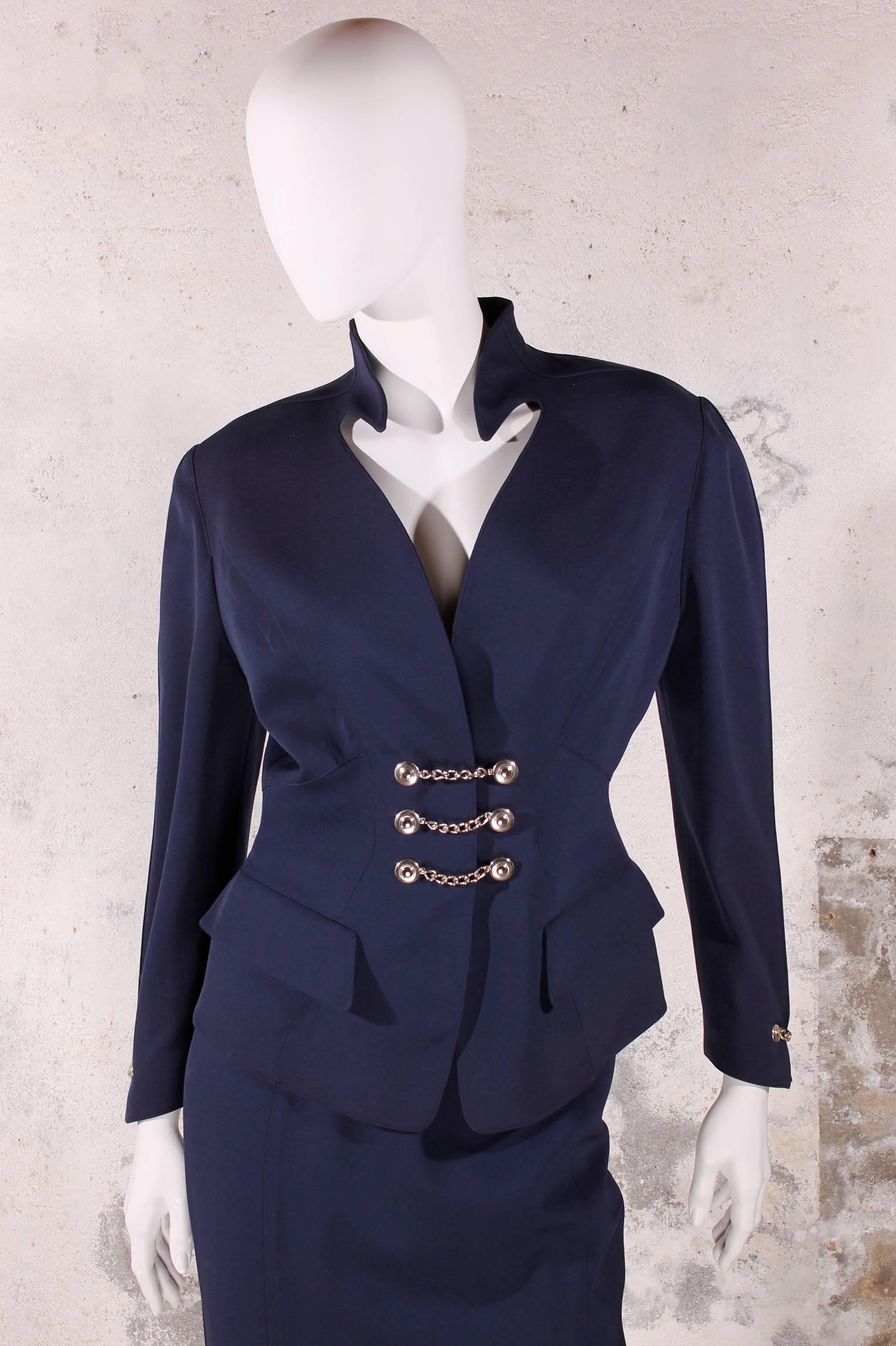 Straight from the 80's: a stunning two piece suit by Thierry Mugler. Dark blue,100% wool and in excellent condition.

The jacket is tailored, has no lapel, but does have a very typical Mugler collar.

Two flap pockets above the hips and a very