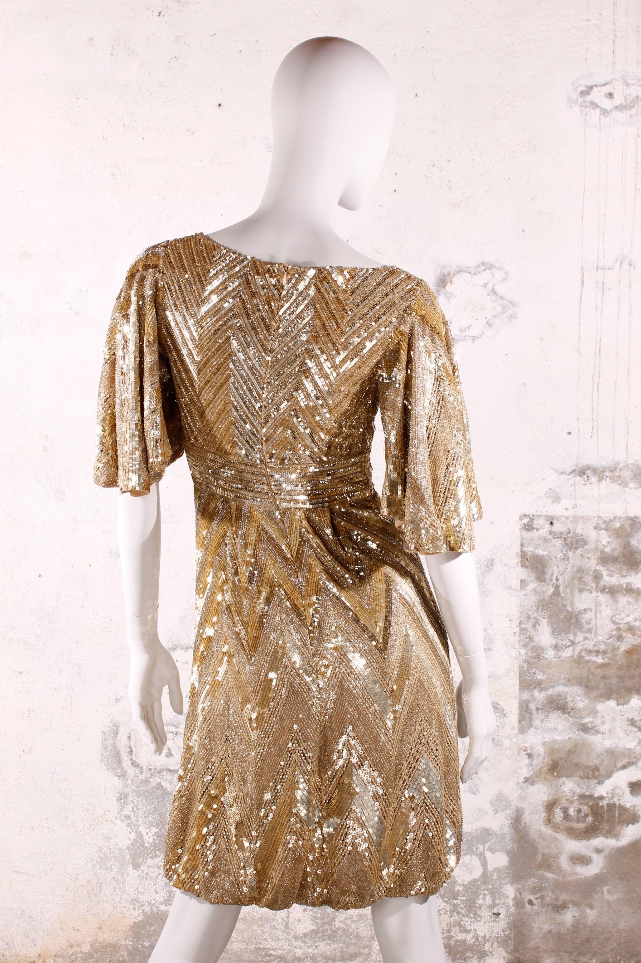 Très chique Elie Saab cocktail dress totally covered with golden sequins and beads in a zig-zag pattern. A festive eye-catcher!

Empire dress with a very low cut V-neck and short sleeves. Dress has knee-length and a balloon skirt. 

A zipper on