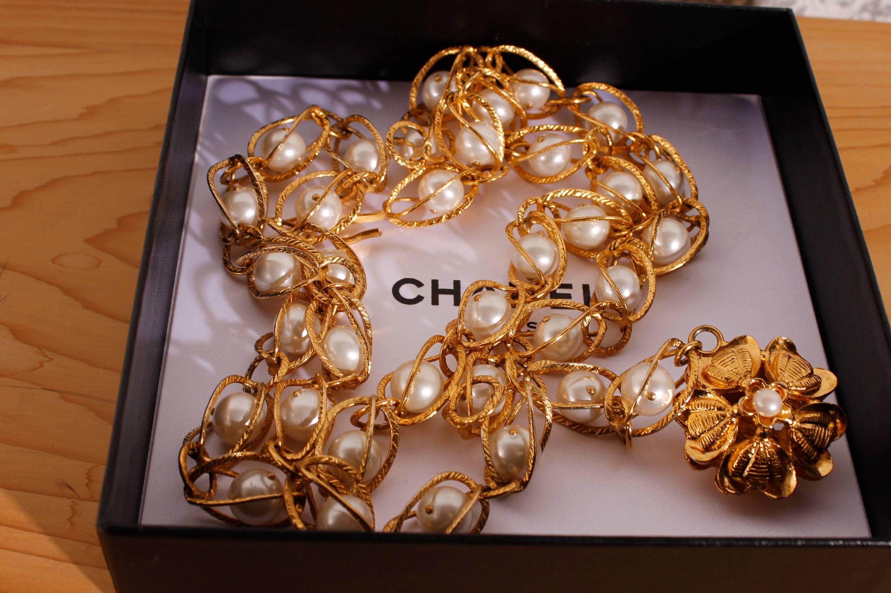 Really fine and chique CHANEL chain belt in goldtone with faux pearls and a flower pendant with a little faux pearl inside. 

Every shackle has a round pearl inside, the end of the chain is double. A large flower pendant at the other end of the