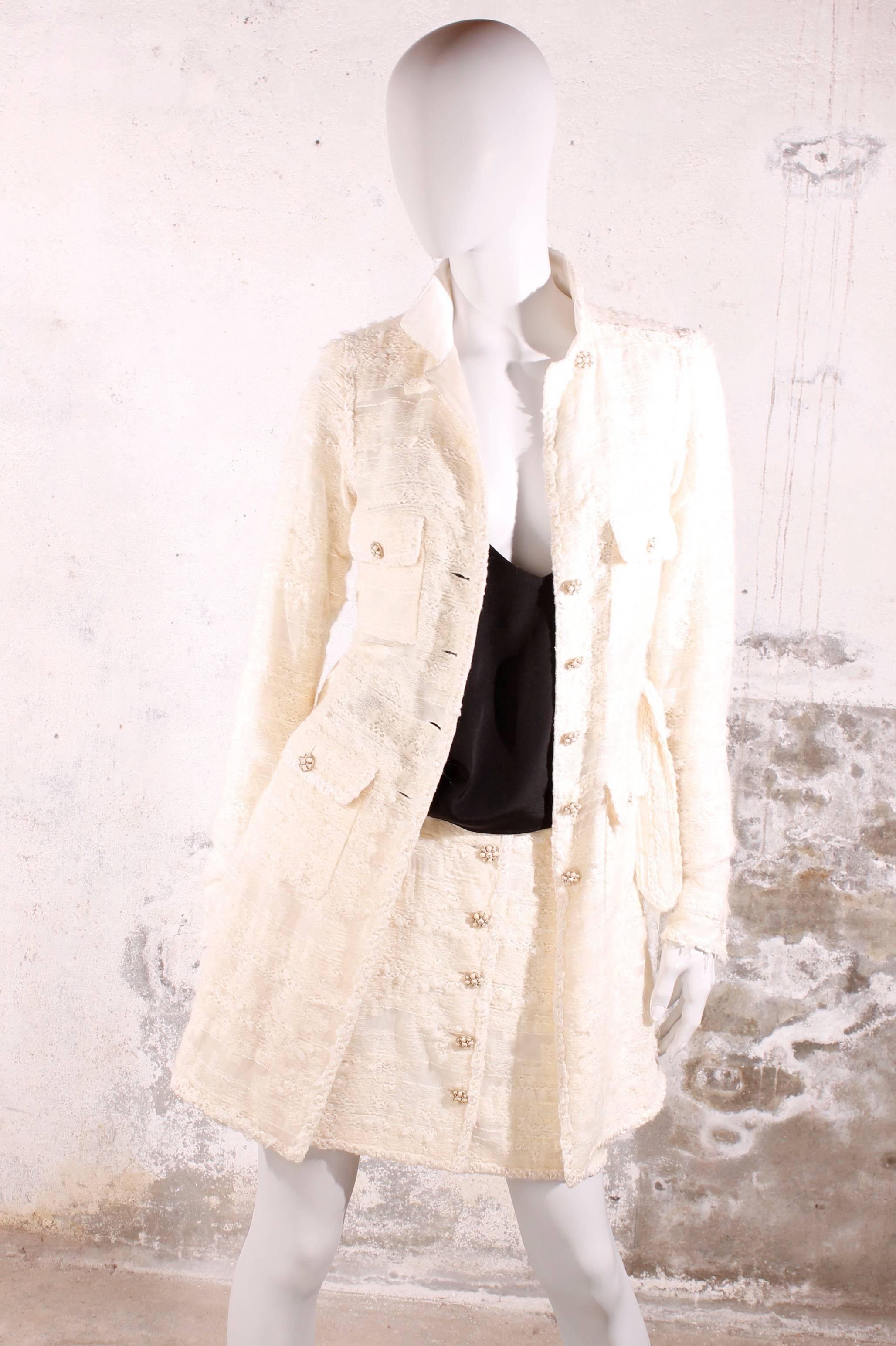 An off-white Chanel fairytale! New and never worn, tags still attached!

This two-piece suit has a long coat and a matching A-line skirt,

A little collar on the jacket and four flap pockets at the front, all with one button made of off-white