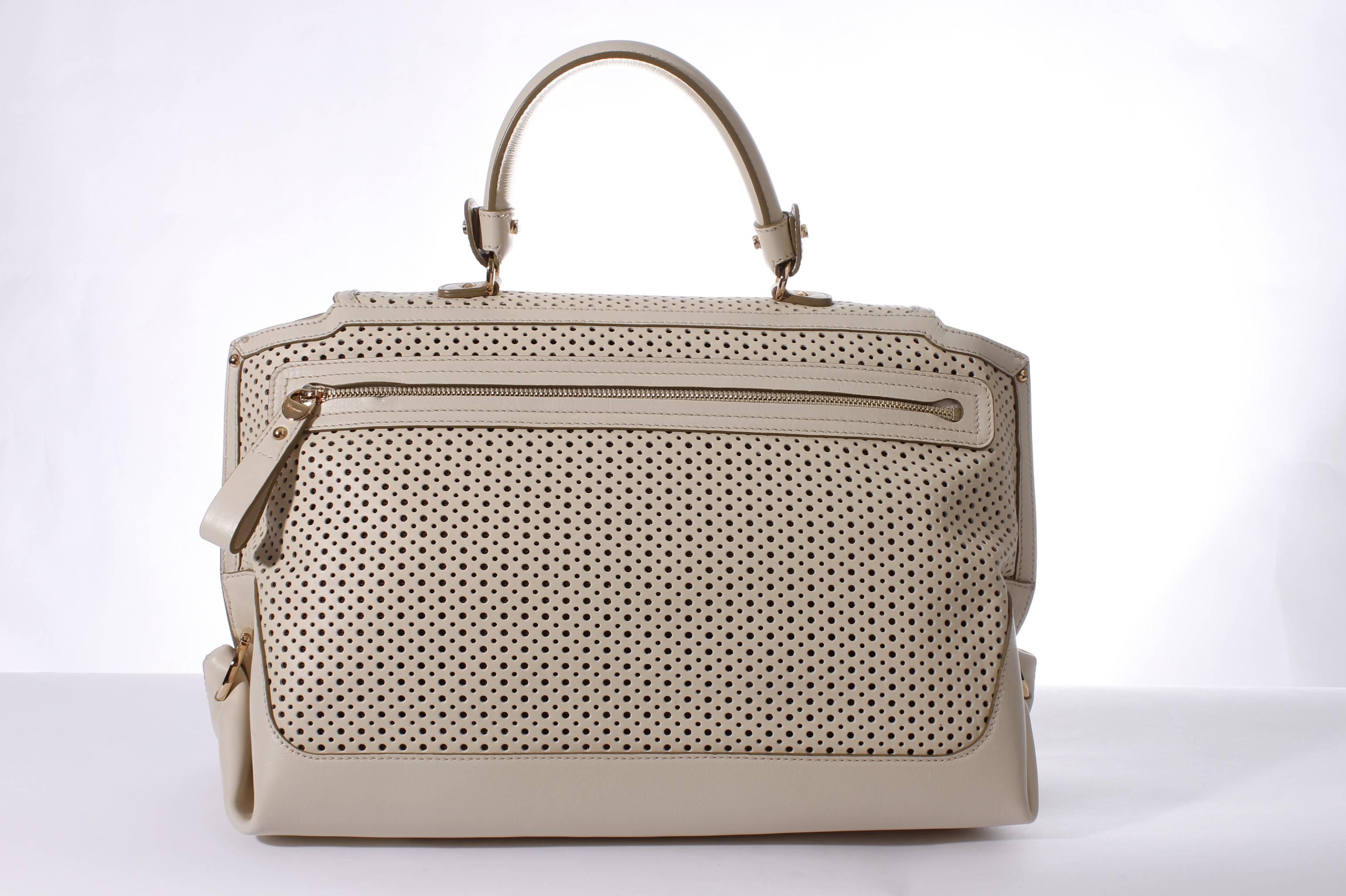 This Salvatore Ferragamo bag is made of pierced leather in off-white. It's the Sofia Large Tote Bag, very stylish!

Shiny golden hardware, a long zipper on the back. Another zipper underneath the flap, this bag closes very well. Lined with dark