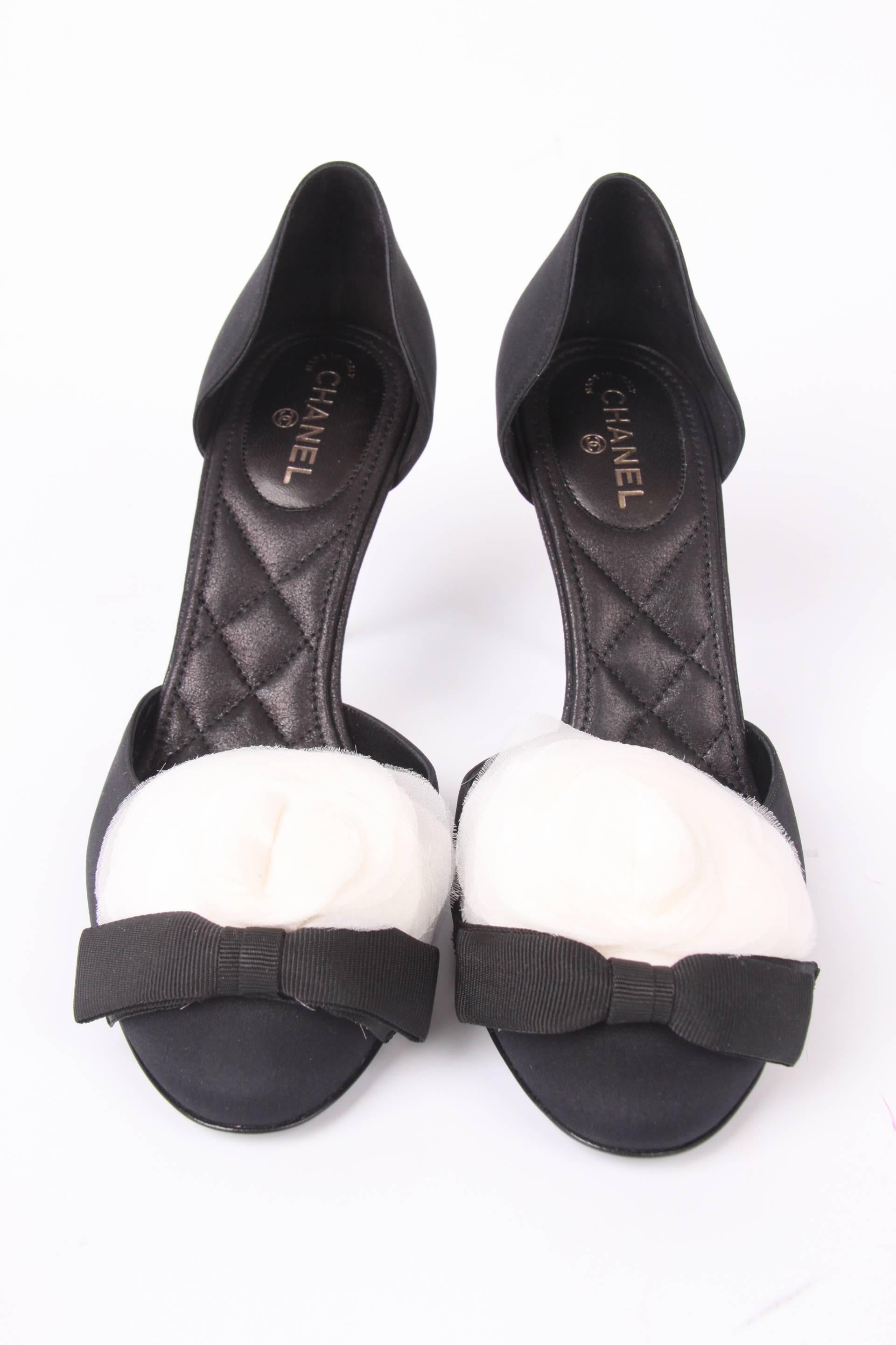 Utterly stunning are these Chanel heels in black satin, a white camellia flower on the toe.

This pair is from the collection of 2005-2006, but they are new and never been worn before, still in their original box. The sole and heel are undamaged,