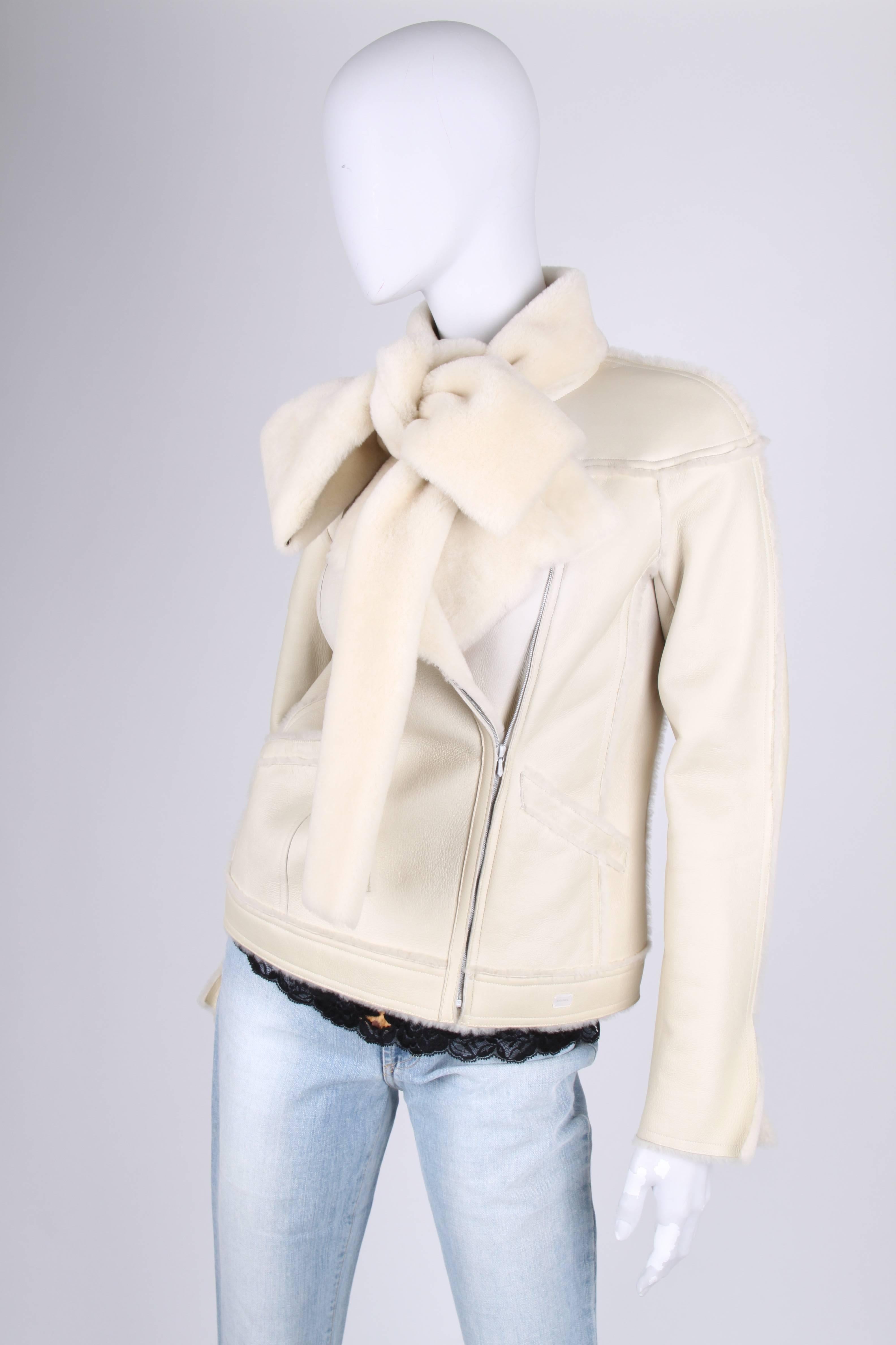 Fantastic lammy by Chanel!

This off-white coat has a diagonal zipper at the front, welt pockets and a collar with a scarf which can be tied into a bow. A slit at the end of the long sleeves. The interior is of course made of nice and soft lambskin