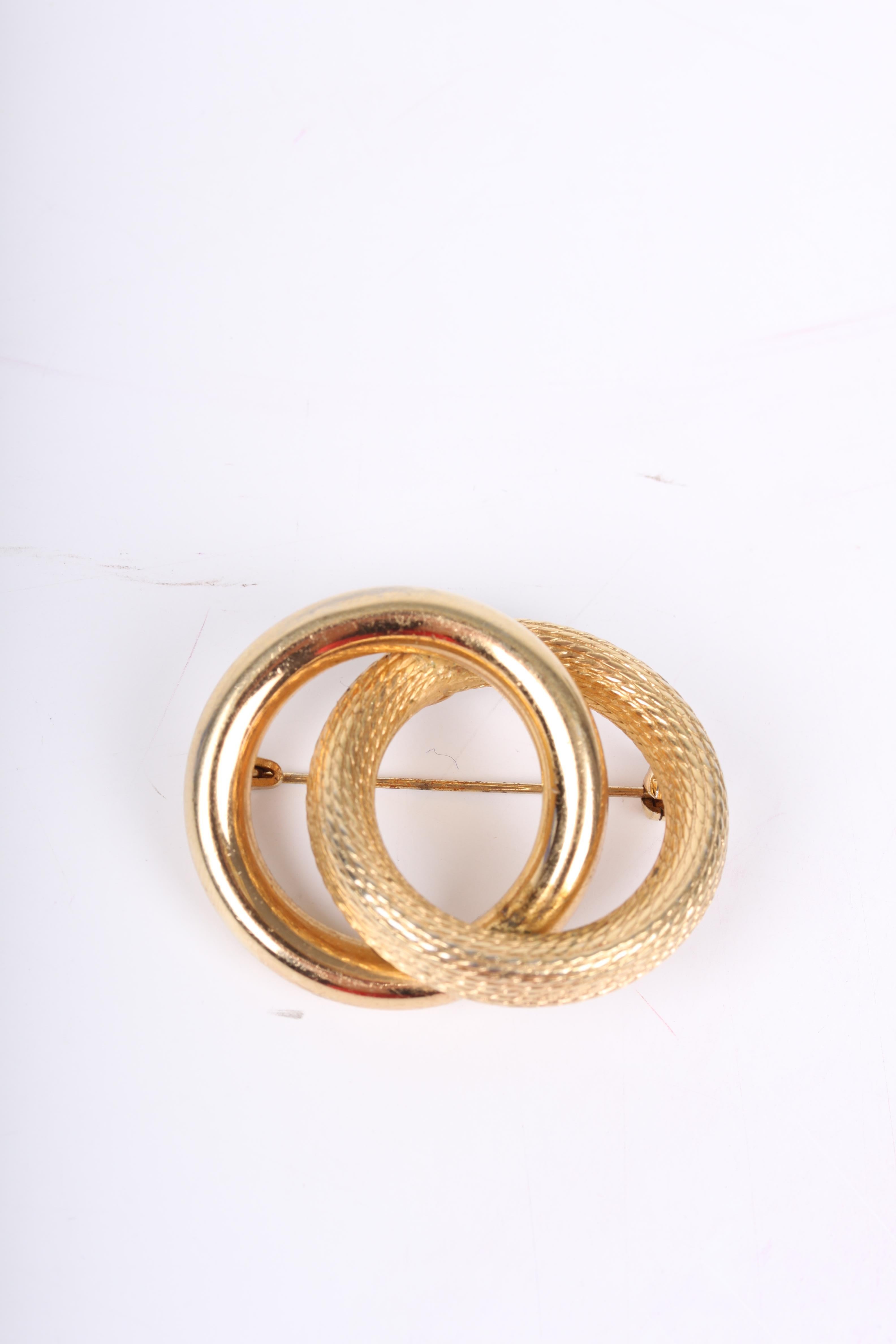 Very old vintage gold-plated Christian Dior brooch. Nice!

The brooch holds two large gold-tone rings; one with a snake skin pattern, the other one smooth. On the back of course a pin, the Christian Dior logo and the year 1958!

Measurements: 4,3 x