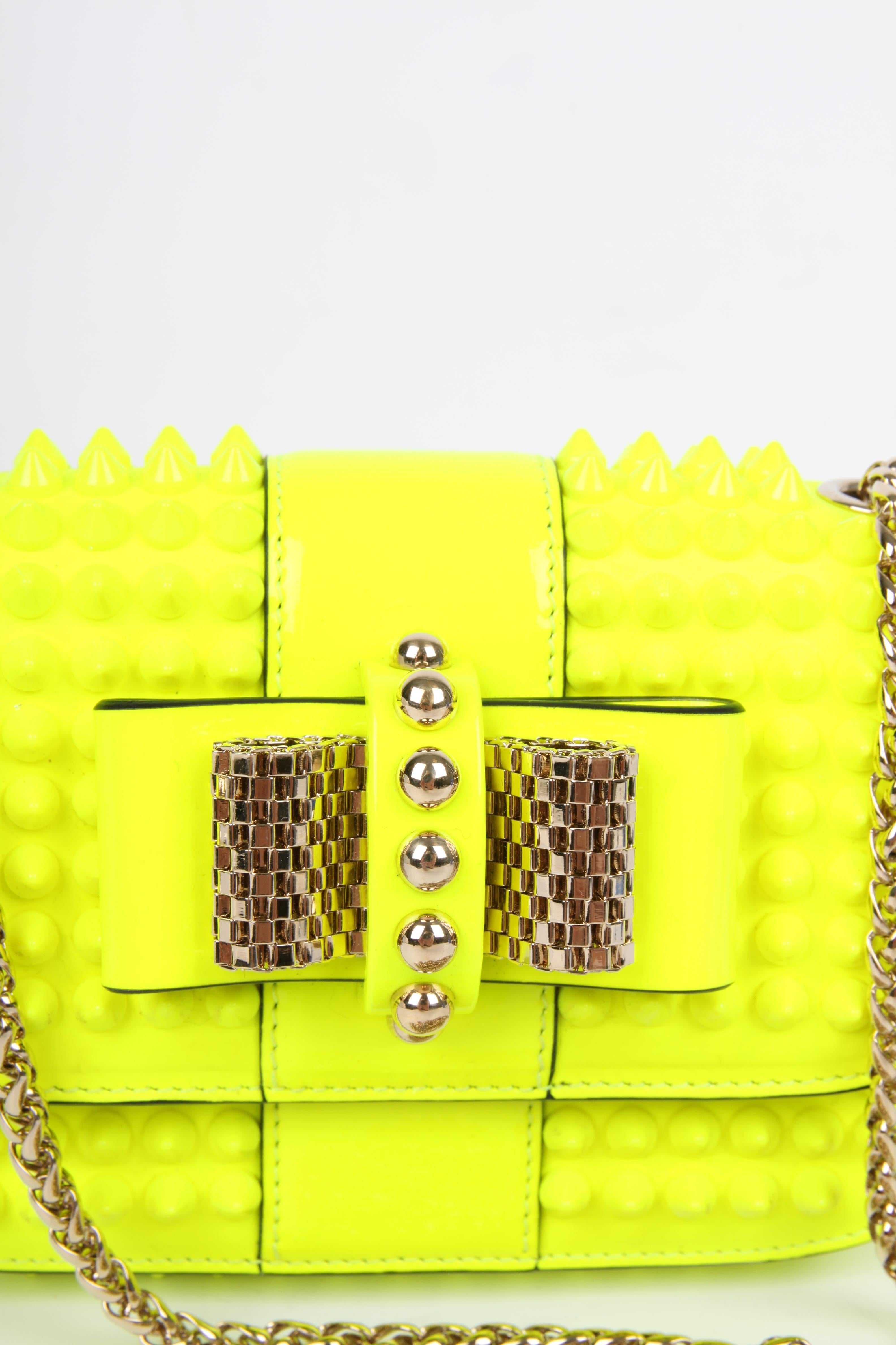 This one really stands out! It's the Sweet Charity Cross Body Bag by Louboutin. A mini bag!

Crafted from neon yellow leather and patent leather with gold-tone hardware. The leather is fully covered with yellow studs. Front closure with a sweet bow
