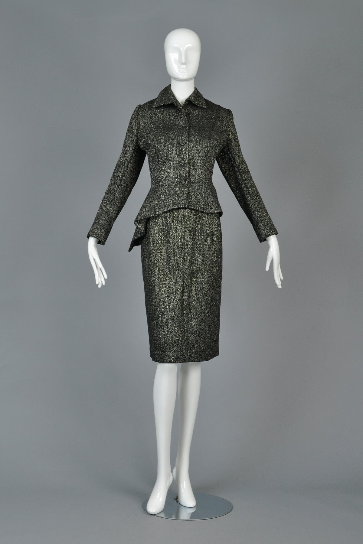 Incredible late 1940s/50s asymmetrical suit. Such a killer find! Classic construction with nipped waist + huge asymmetrical padded peplum. Black wool body with metallic lurex threads running throughout. Excellent vintage condition - missing the top