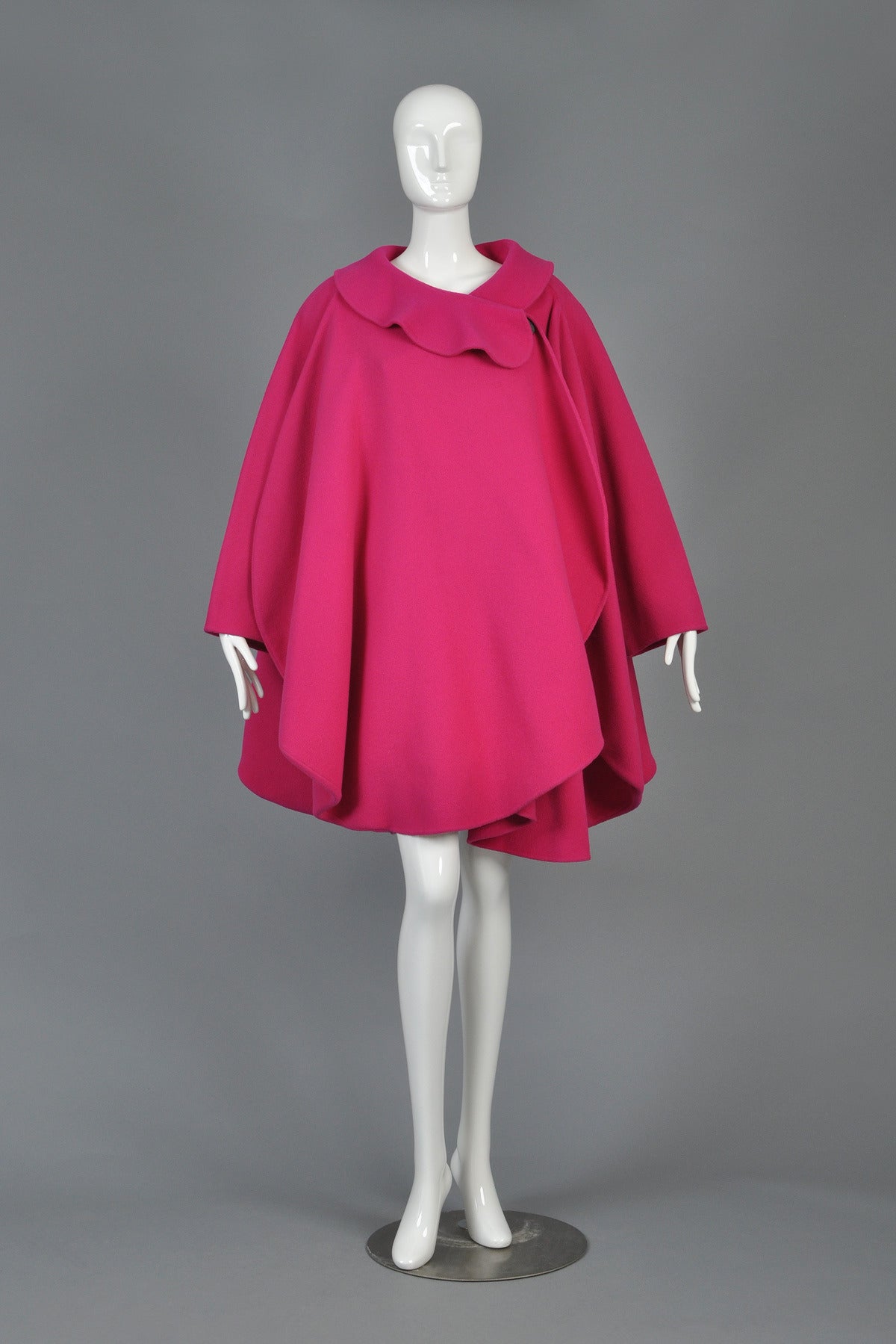 1987 Pierre Cardin Haute Couture Fin-Backed Coat.  Well documented and coveted piece. Truly iconic, one-of-a-kind find in a classic Cardin avant garde cut. Heavy-weight magenta wool with single asymmetrical button closure and slightly ruffled