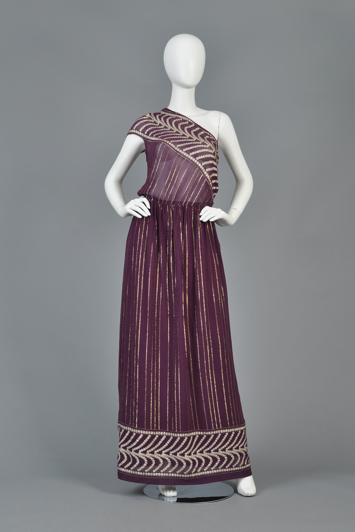 Recently reduced from $595 to $395

Beautiful 1970s Grecian inspired gown. Incredible piece! Beautiful plum-colored sheer rayon with metallic silver and gold lurex threads running throughout. Ultra sheer one-shouldered bodice with simple short