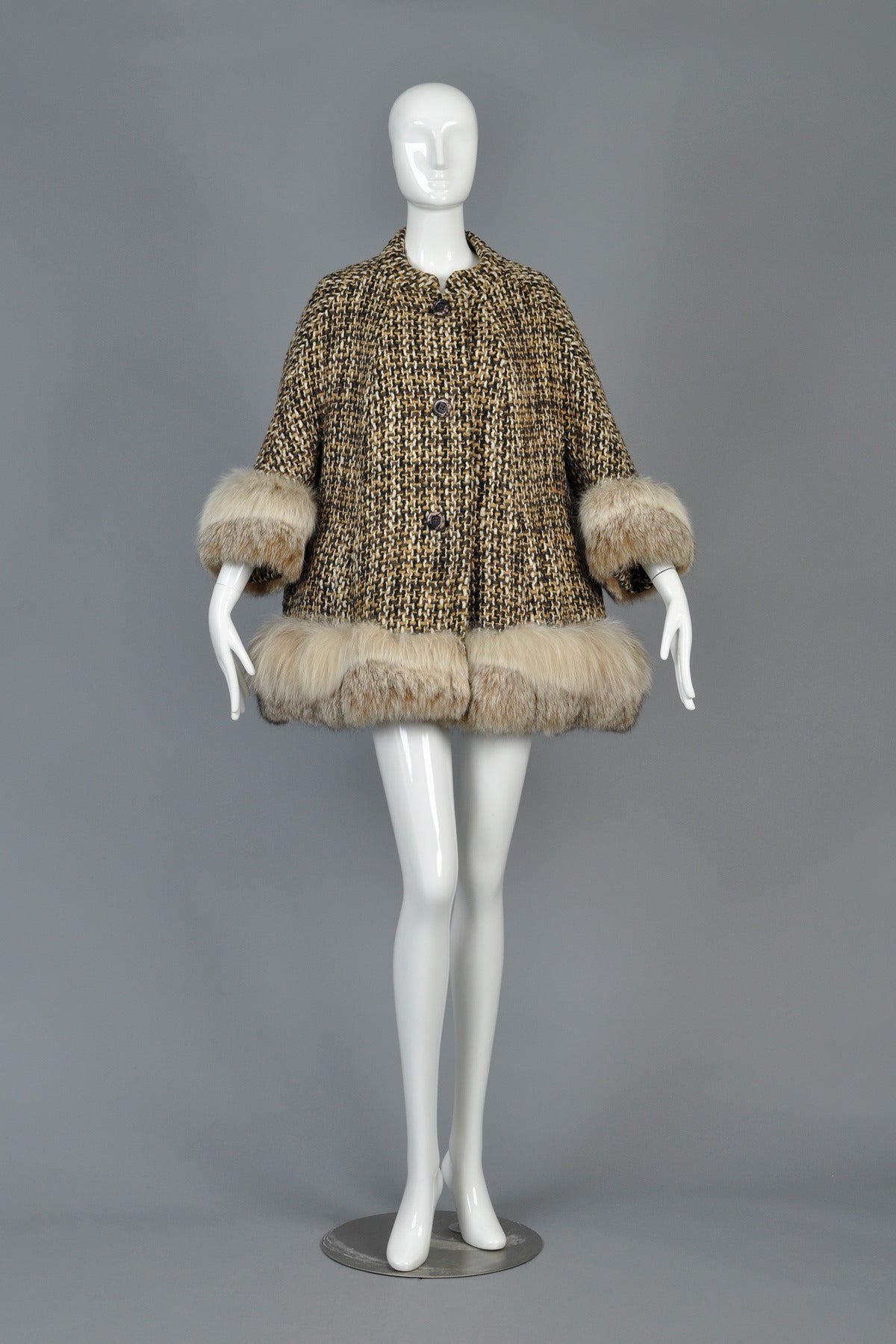 Absolutely adorable 1960s cropped tweed swing coat with genuine lynx fur trim. We LOVE the lines of this little piece! Jacket features a button front with besom pockets, high neck + 3/4 length sleeves. Fully lined. Pristine vintage condition - fur