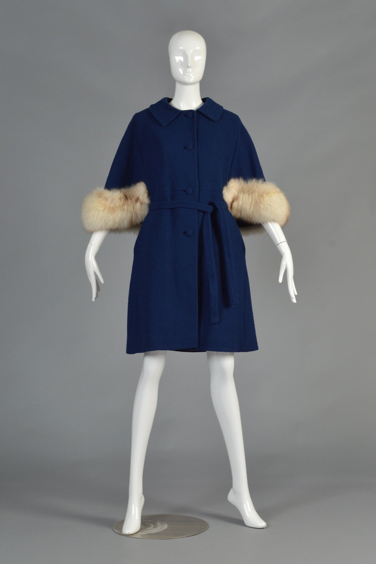 Superb vintage 1960s navy blue wool cape coat with fox trim. Absolutely awesome, on trend vintage find! Button front with slightly flared hem, side pockets, optional belt + flared cape back with HUGE genuine blue fox fur trim. We love the tiny tab