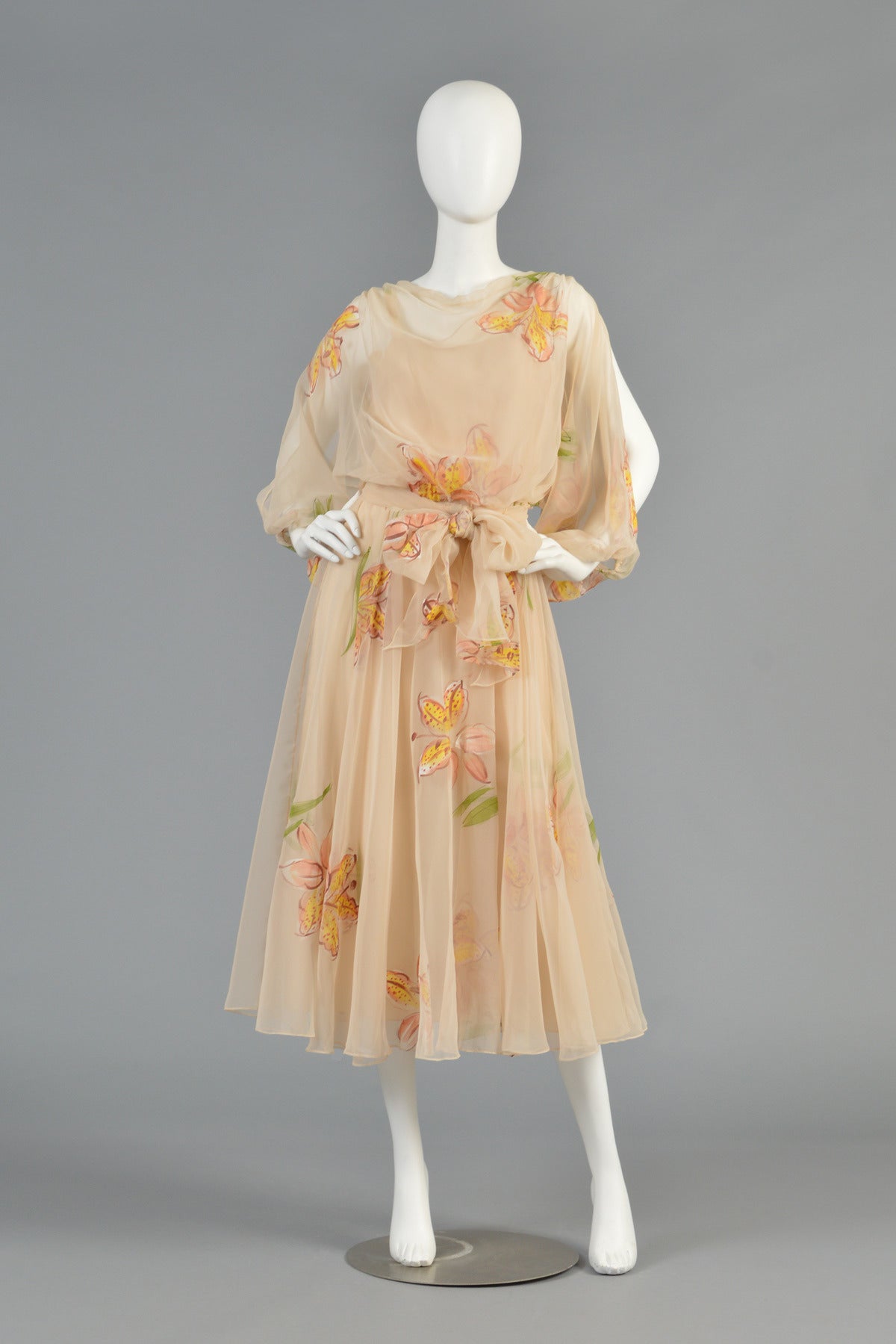 Beautiful 1970's pale peachy-nude chiffon dress by Mignon. An amazing find and perfect for all of your spring and summer engagements! Sheer chiffon body with high draped neck, nipped waist, full skirt and billowing open sleeves. Lovely reverse