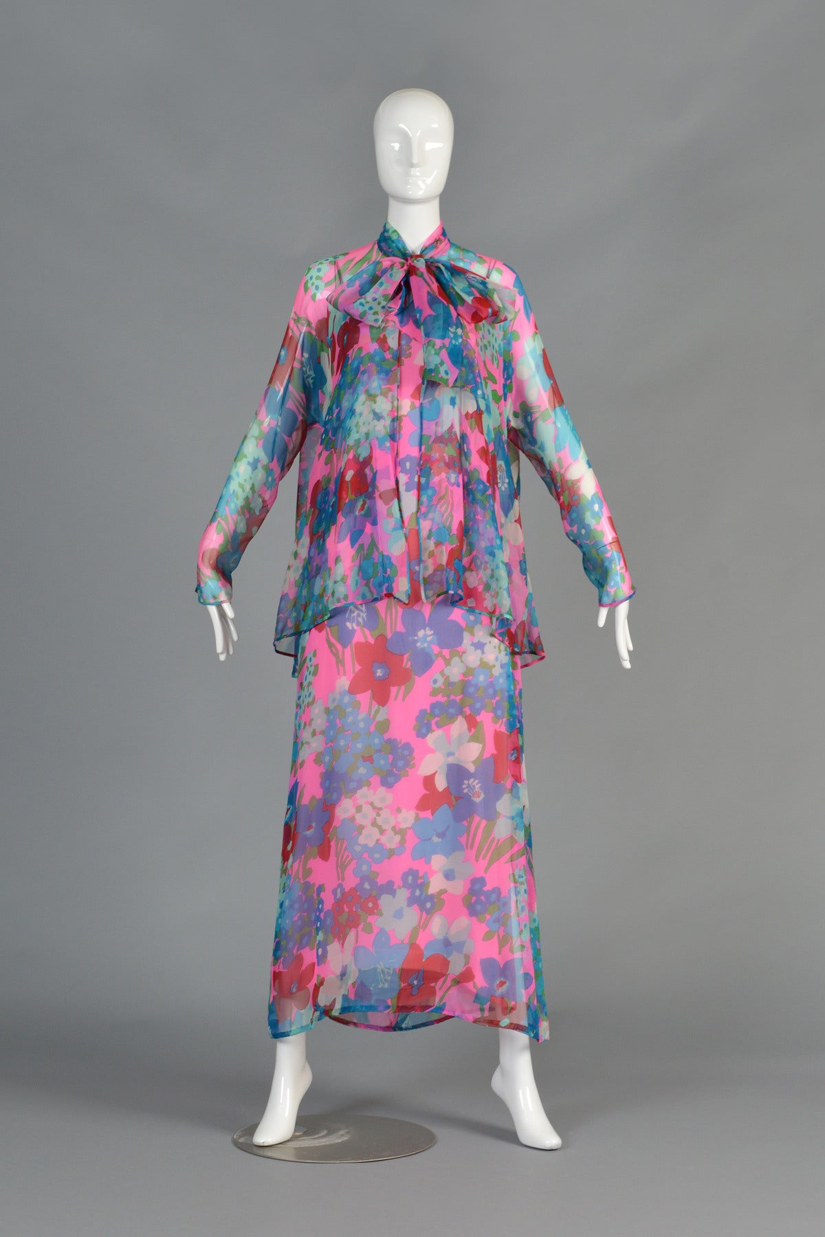 Incredible vintage 1970s silk chiffon dress + jacket by Adele Simpson. Graphic pink + purple florals. Simple shift style maxi dress with double spaghetti straps. Sheer chiffon outerlayer with solid under dress. Matching longsleeve, fishtail draped