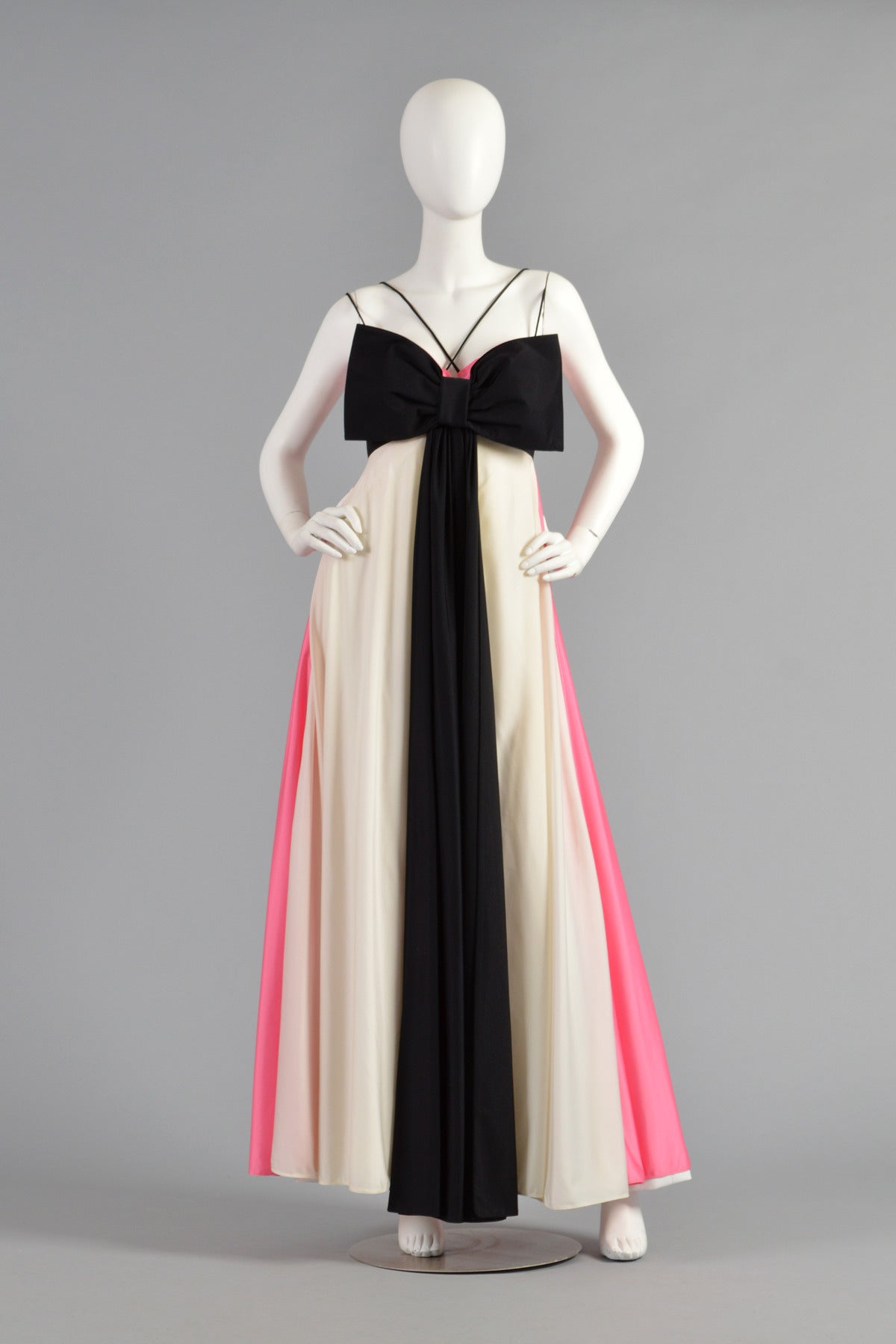Incredible vintage 1970s pink, black + white maxi dress by Les Wilk. Truly a unique + stunning gem. Pink + white vertically striped maxi gown features a huge full sweep. The empire waist bodice features the most massive black bow tie front with long