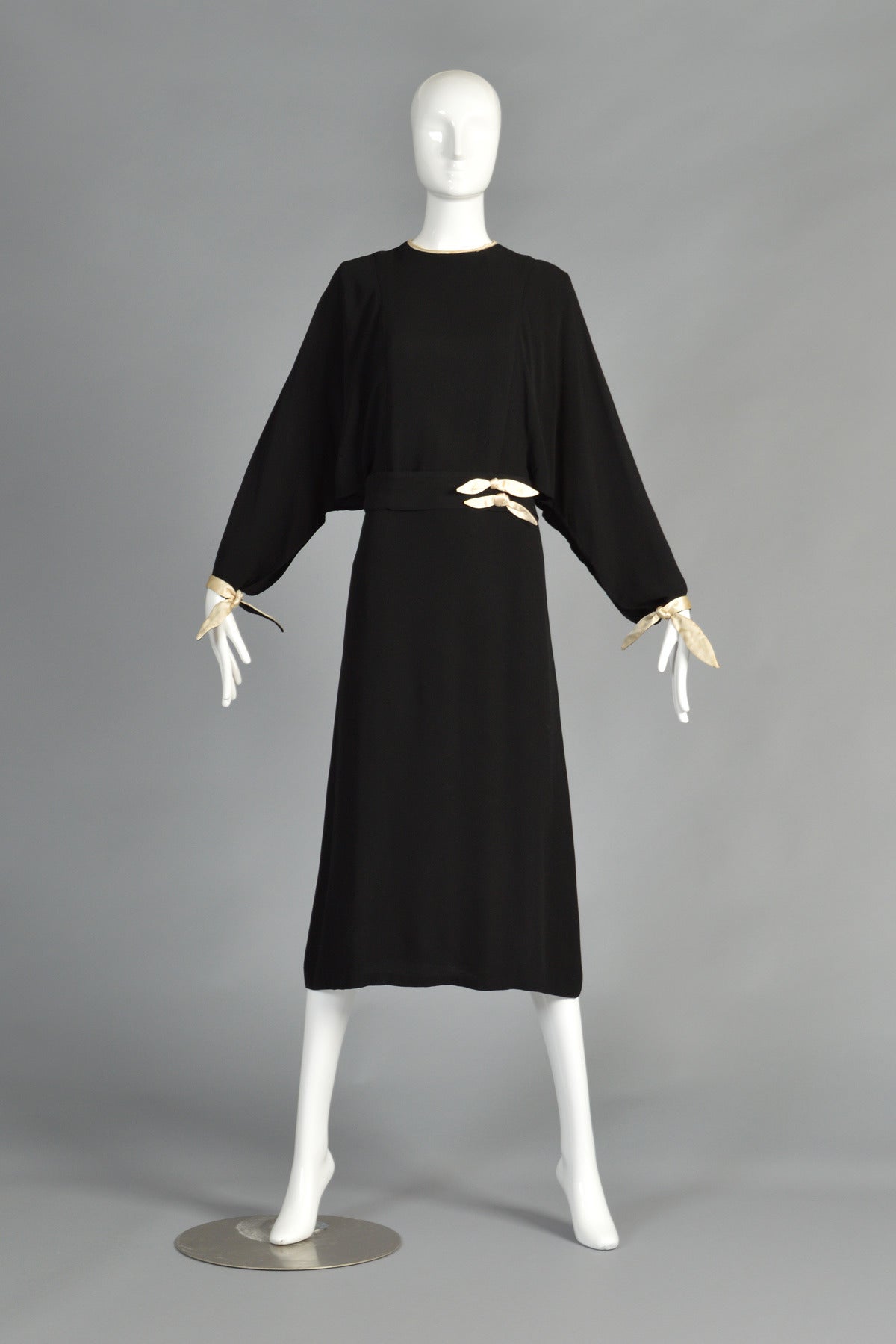 Lovely 1930s black crepe dress with the simplest and most elegant details. Classic high neck construction with nipped waist and draped sleeves that are open on the underside of each. Ivory silk satin ties at each wrist are the only things holding