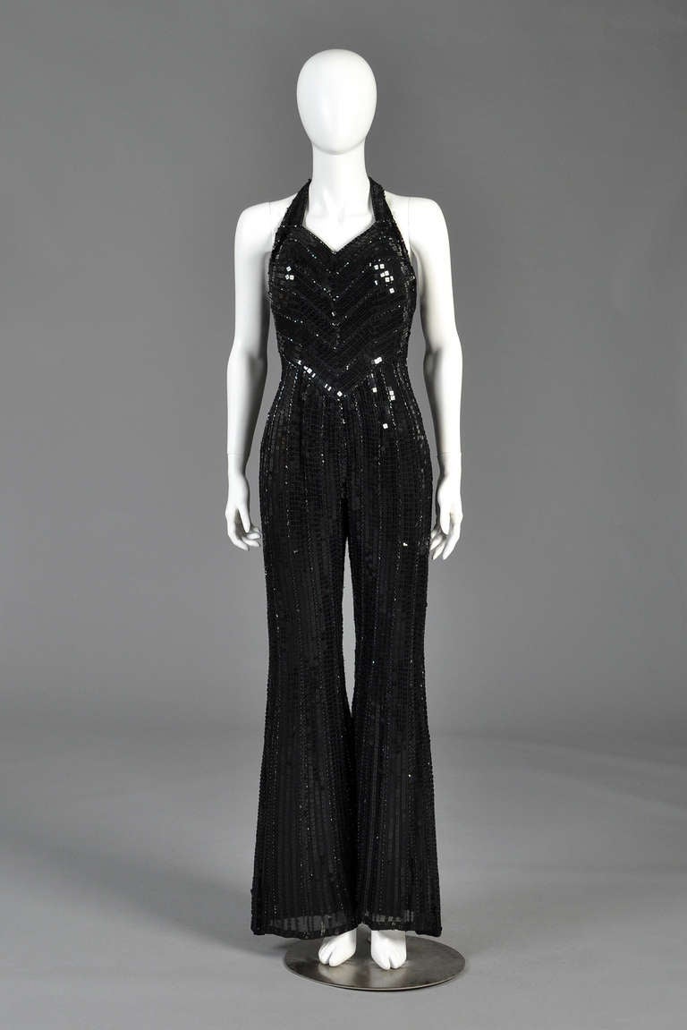 Kapow! Incredible vintage D&G Dolce & Gabbana sequin jumpsuit. Flare legs. Plunging halter neckline with completely exposed back. Entirely encrusted in black square sequins + beads. Striped chevron pattern on bodice. A few missing sequins here and