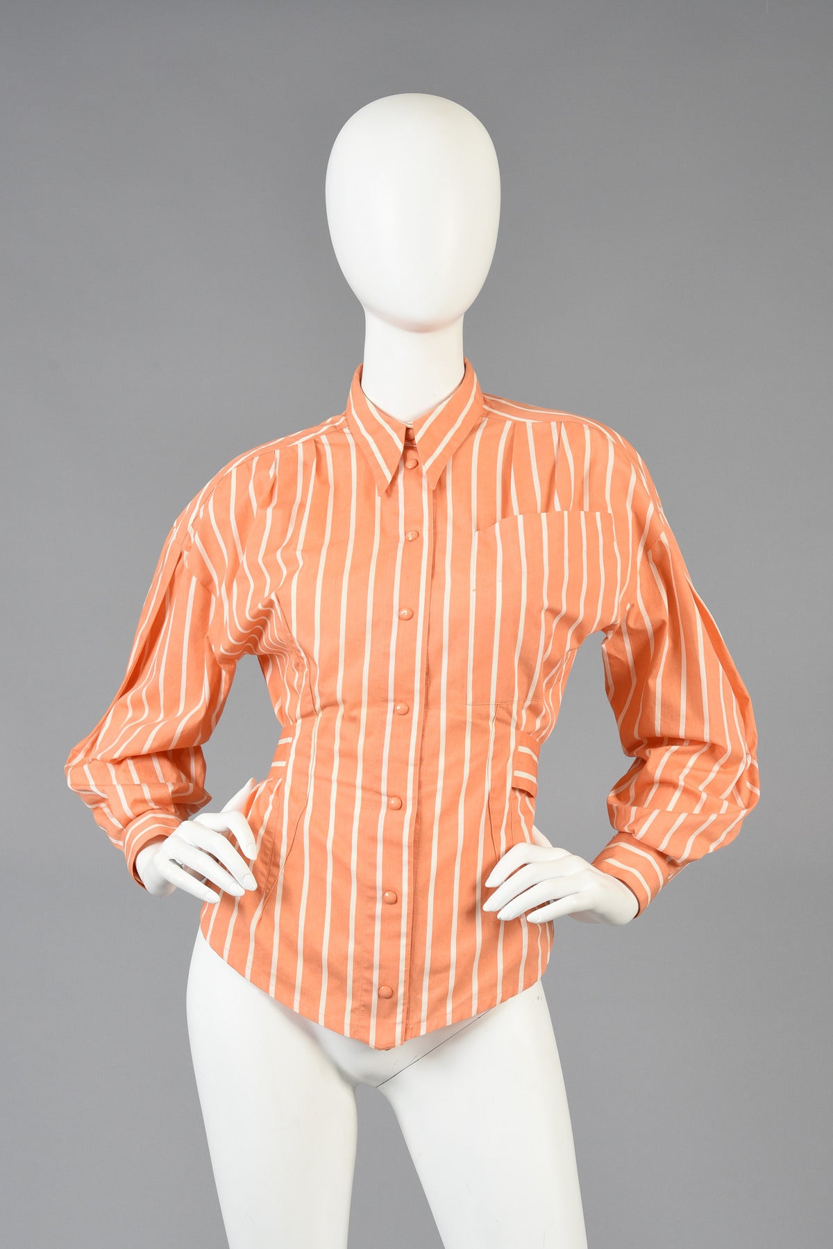 Super great 1980's cotton blouse by Thierry Mugler. Such a great find! Sherbet colored cotton with white pinstripes makes this such a feel good little piece! Snapping front with huge pocket, cutout back and attached belt. The perfect piece for