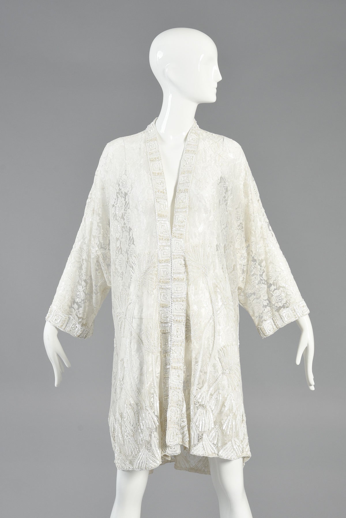 Gorgeous 1980's white beaded lace draped jacket. Incredible piece and our all-white ghost mannequins just can't do it justice!

Designed to be worn open, this piece features a sheer floral lace body and wide, kimono-like sleeves. Beautiful Art