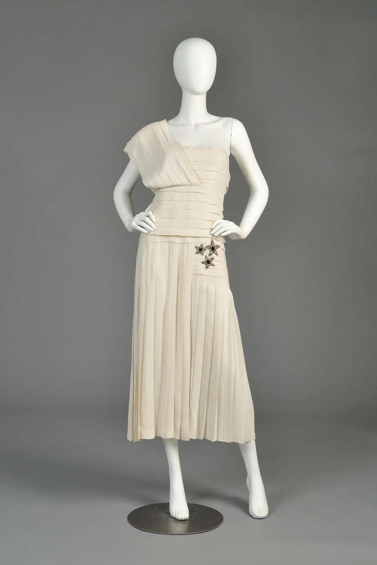 Lovely 1980s Bernard Perris ivory Grecian-pleated silk gown. Classic bodice with single shoulder, nipped waist and flared hips. We love the contrasting horizontal and vertical pleats! Also features a hidden side zipper and massive front slit.